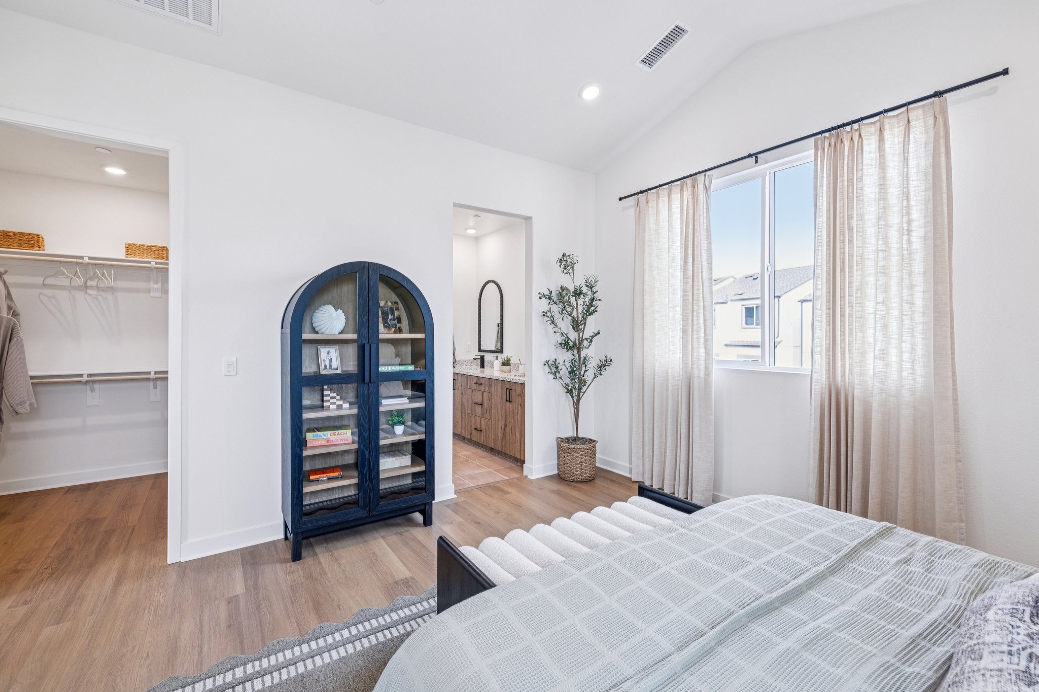 Model home large primary bedroom with en-suite bathroom and vaulted ceilings