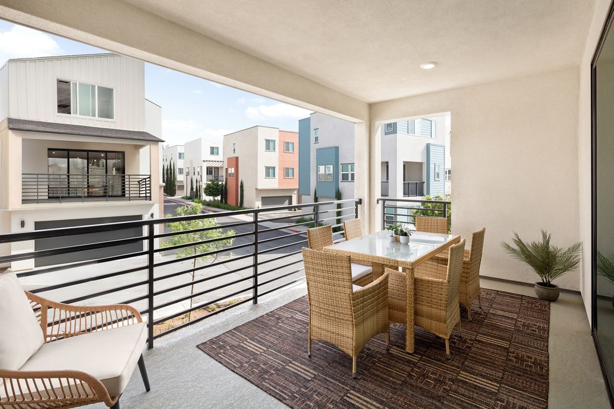 Model home covered deck with seating area and sliding doors offering neighborhood views
