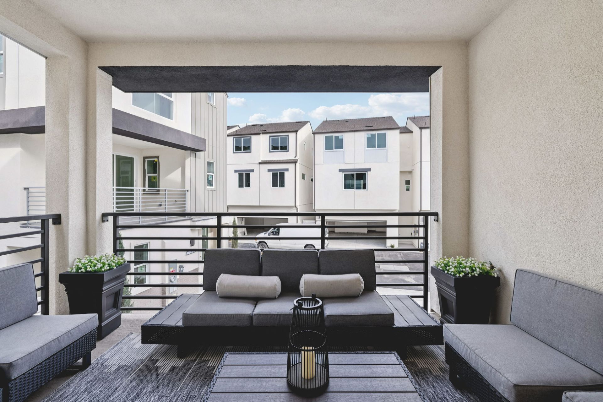 Model home covered deck with seating area and sliding doors offering neighborhood views