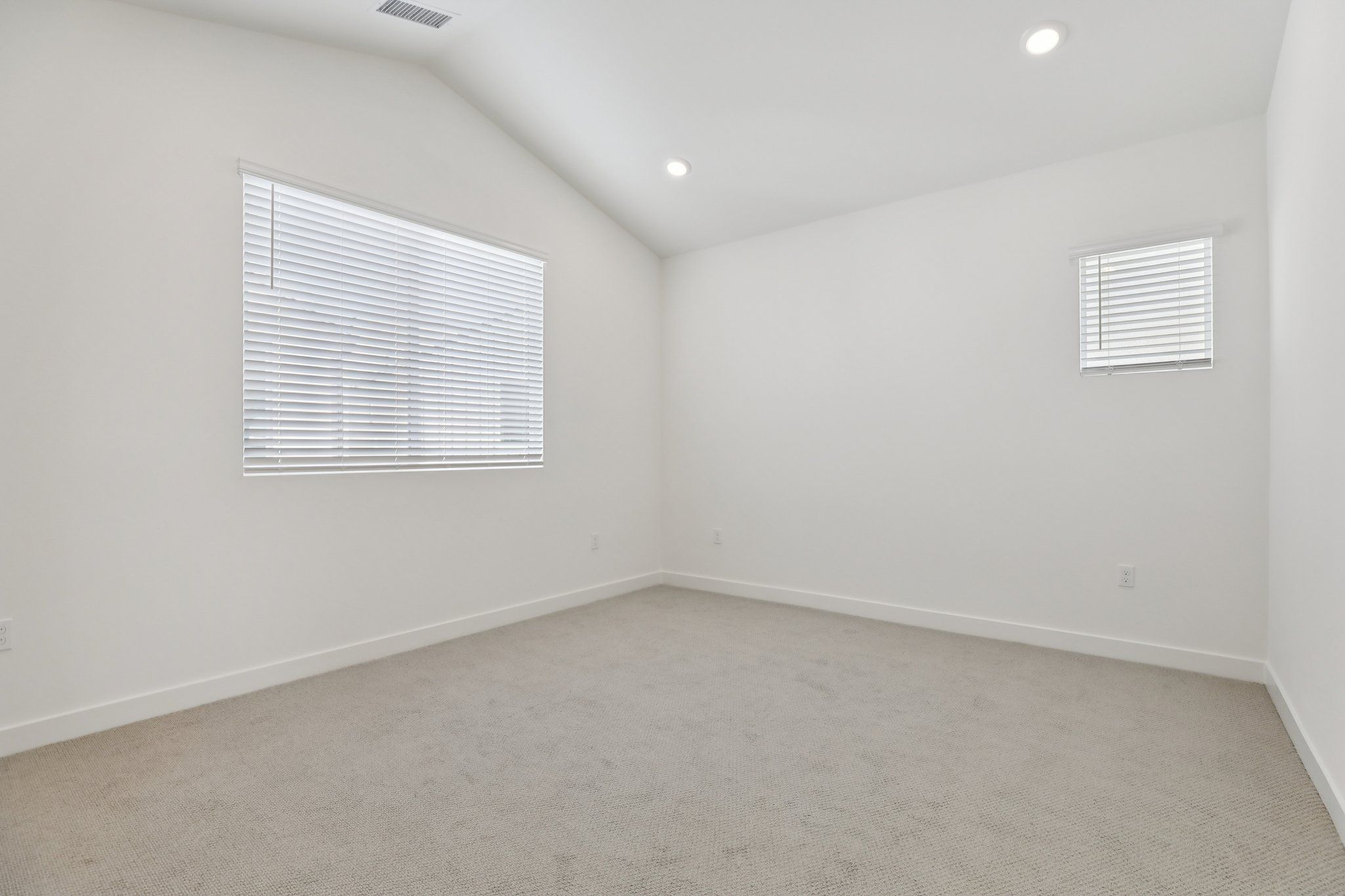 Open primary bedroom with a bright, large window and vaulted ceiling