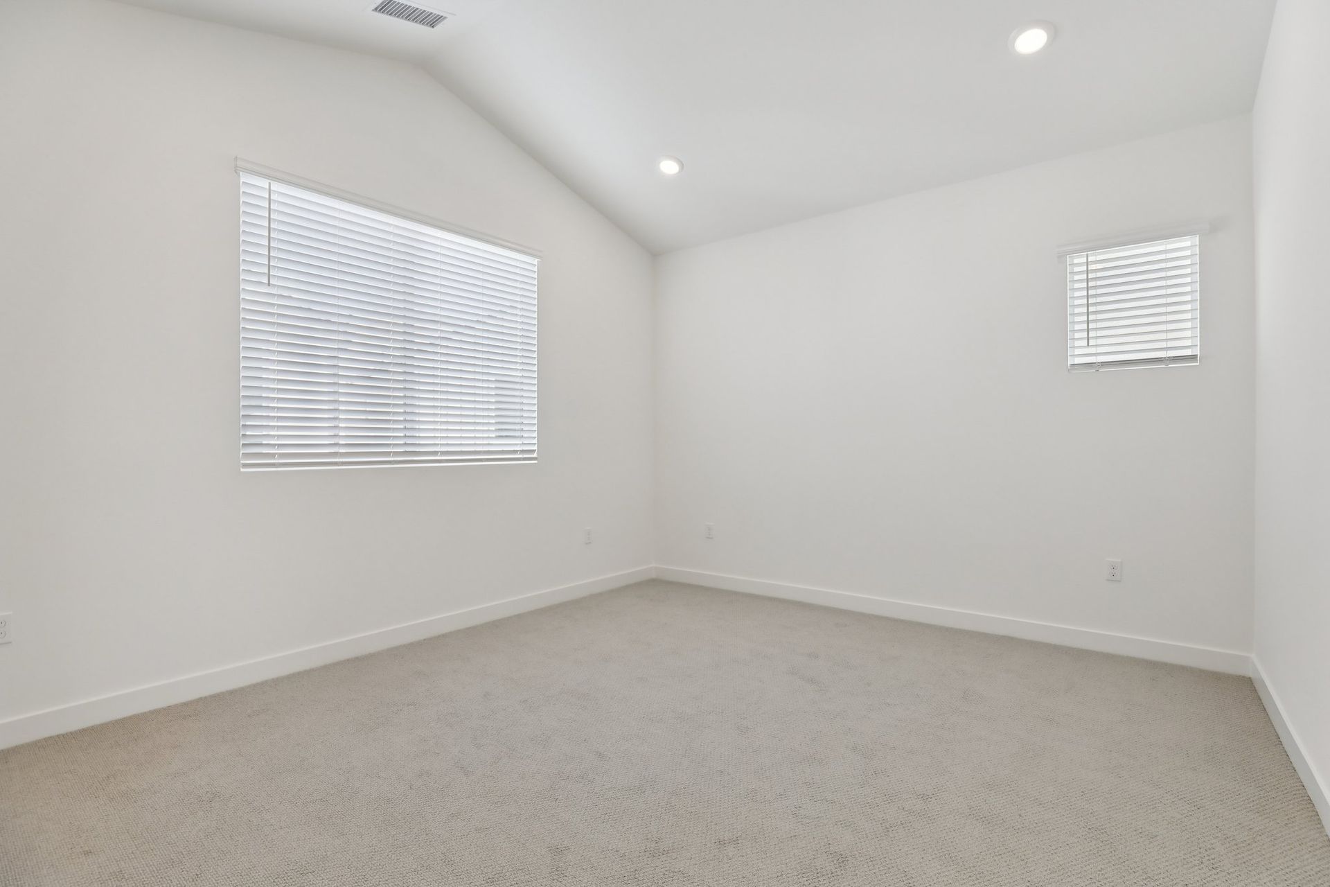 Open primary bedroom with a bright, large window and vaulted ceiling