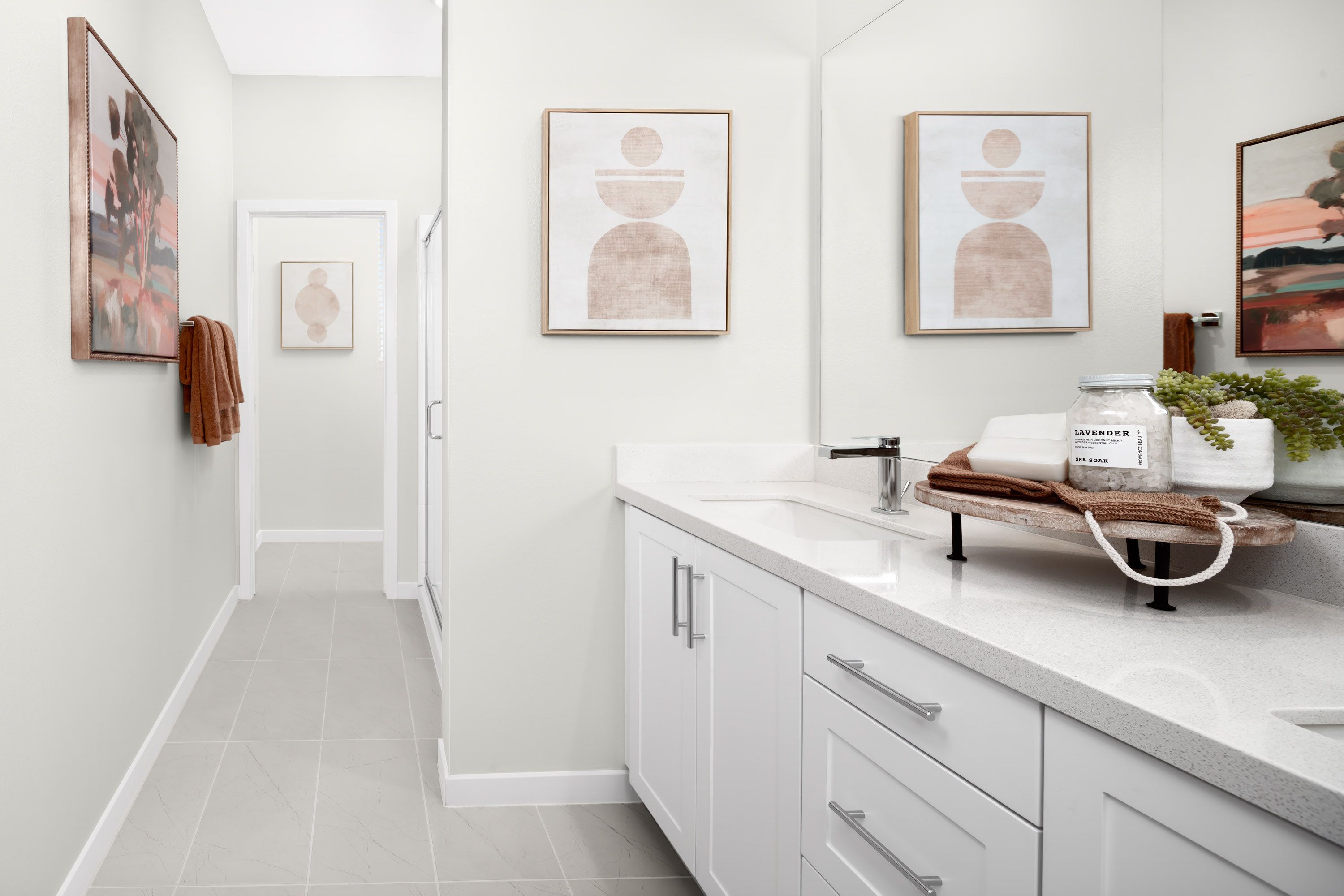 Plan 1 model home primary bathroom featuring a dual vanity setup and a shower.