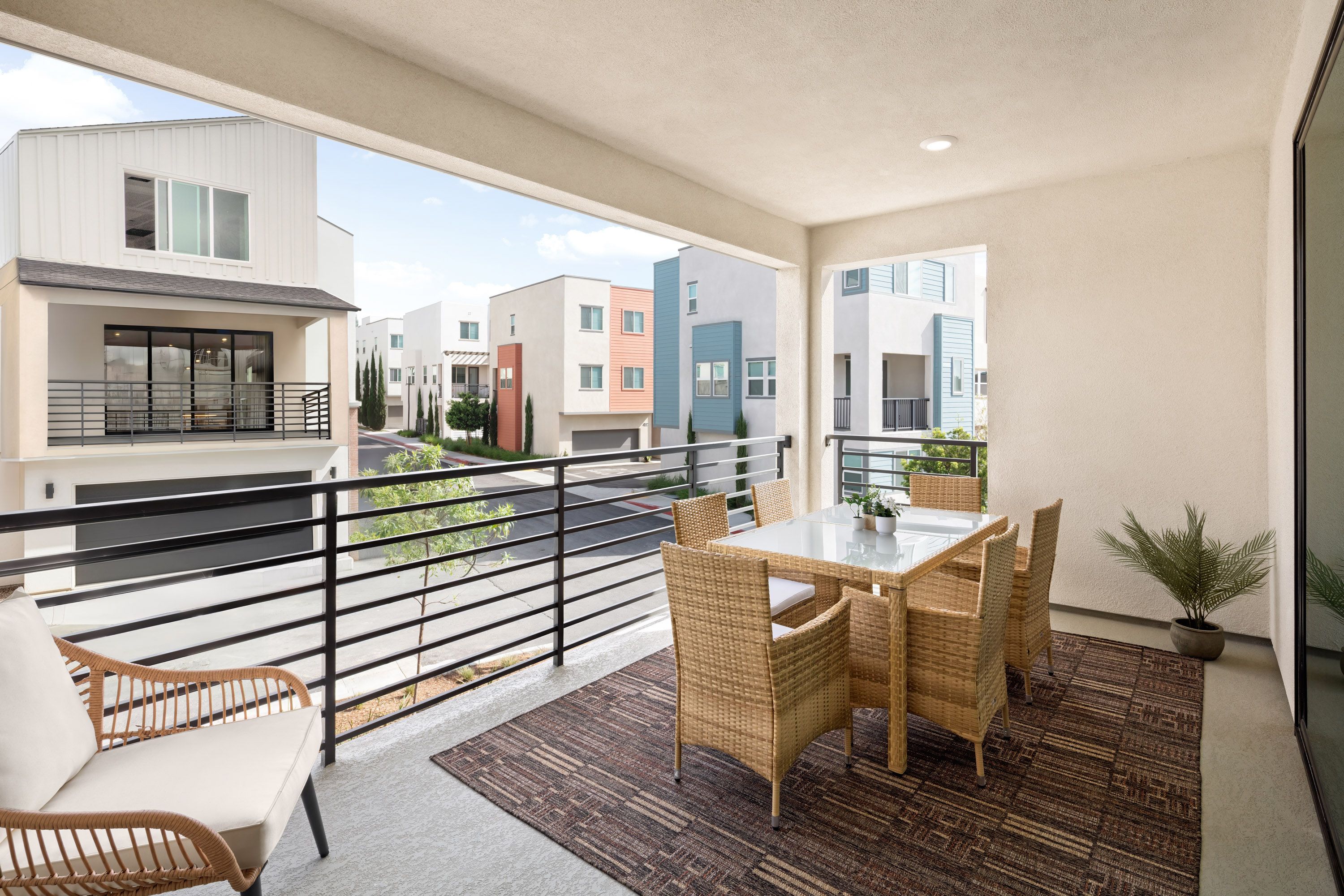 Model home covered deck with seating area and sliding doors offering neighborhood views