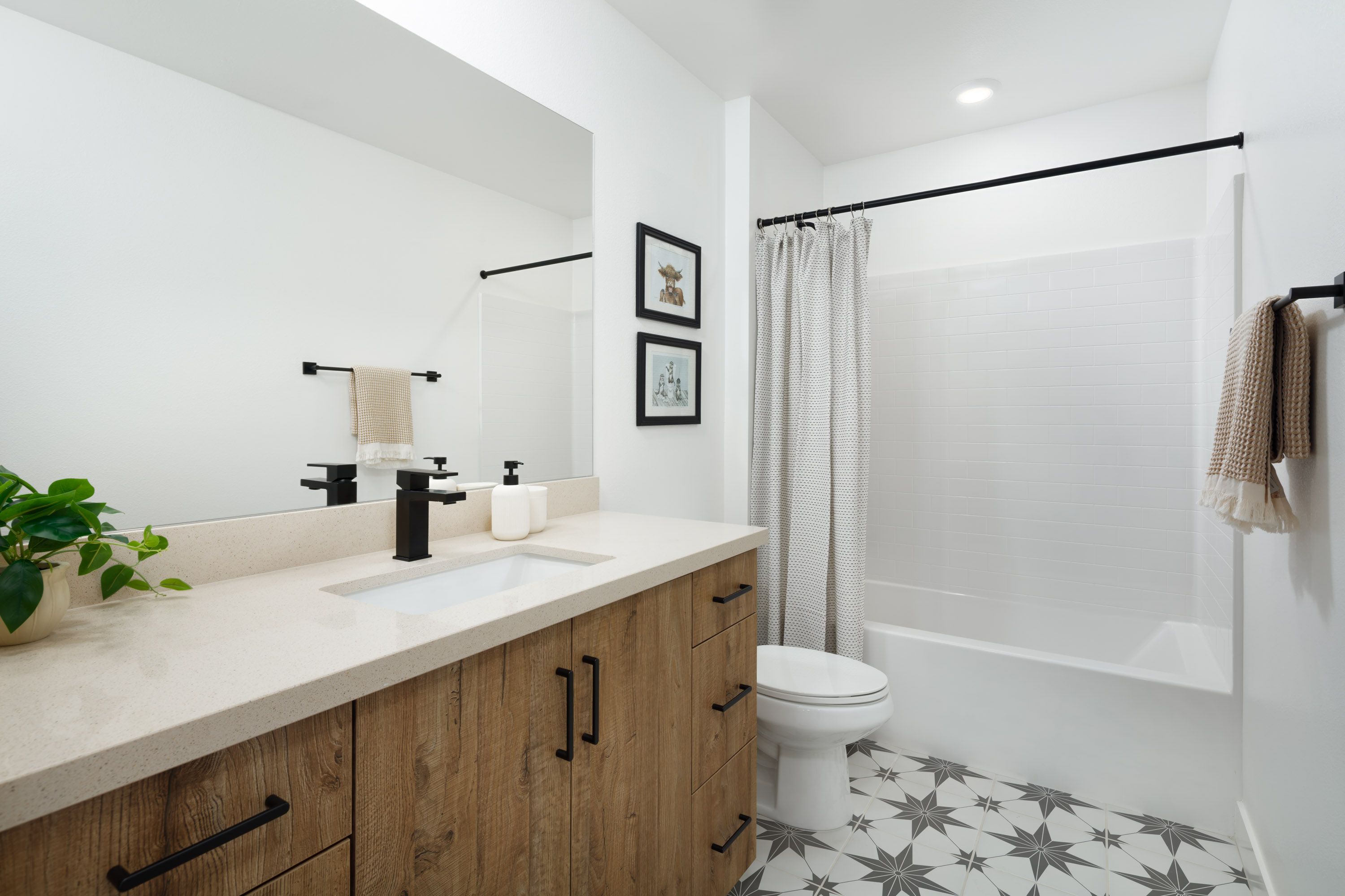 Model home secondary bathroom with a bright layout, single vanity, and shower