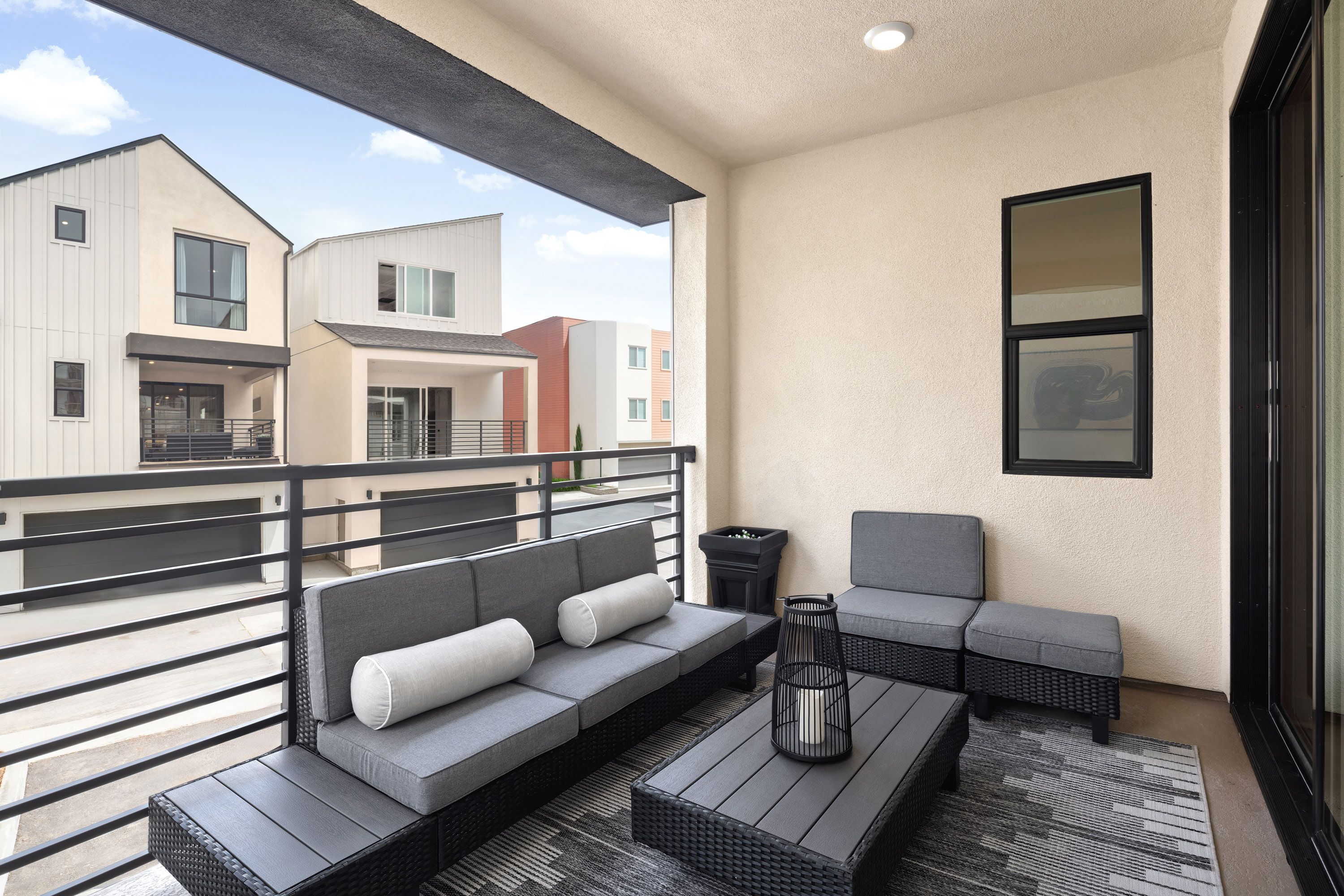 Model home covered deck with seating area and sliding doors offering neighborhood views
