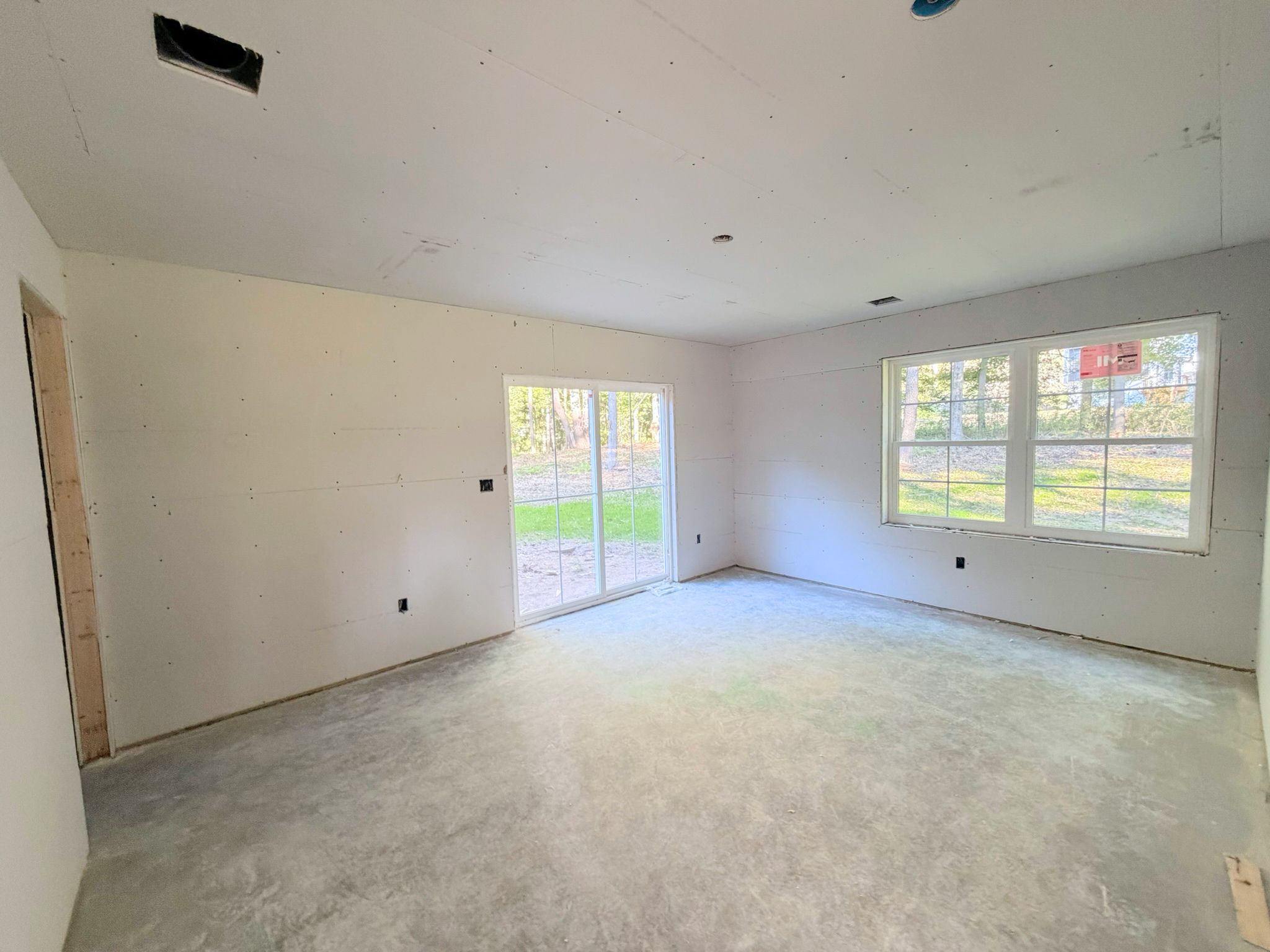 Generously sized, the recreation room with sliding doors is taking shape with drywall complete and multiple windows to provide abundant light.