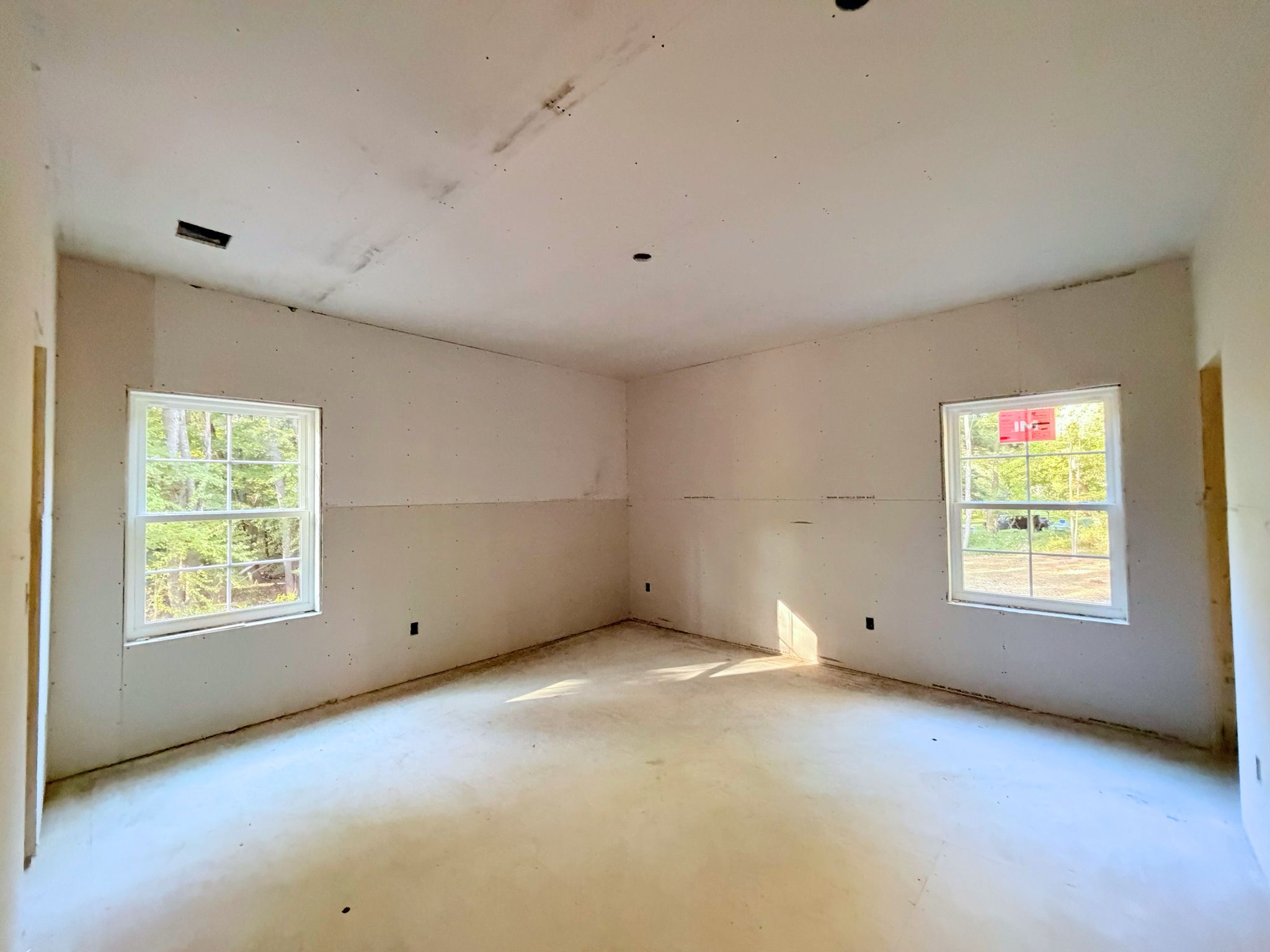 Construction progress continues in the spacious master bedroom featuring multiple windows and abundant natural light.