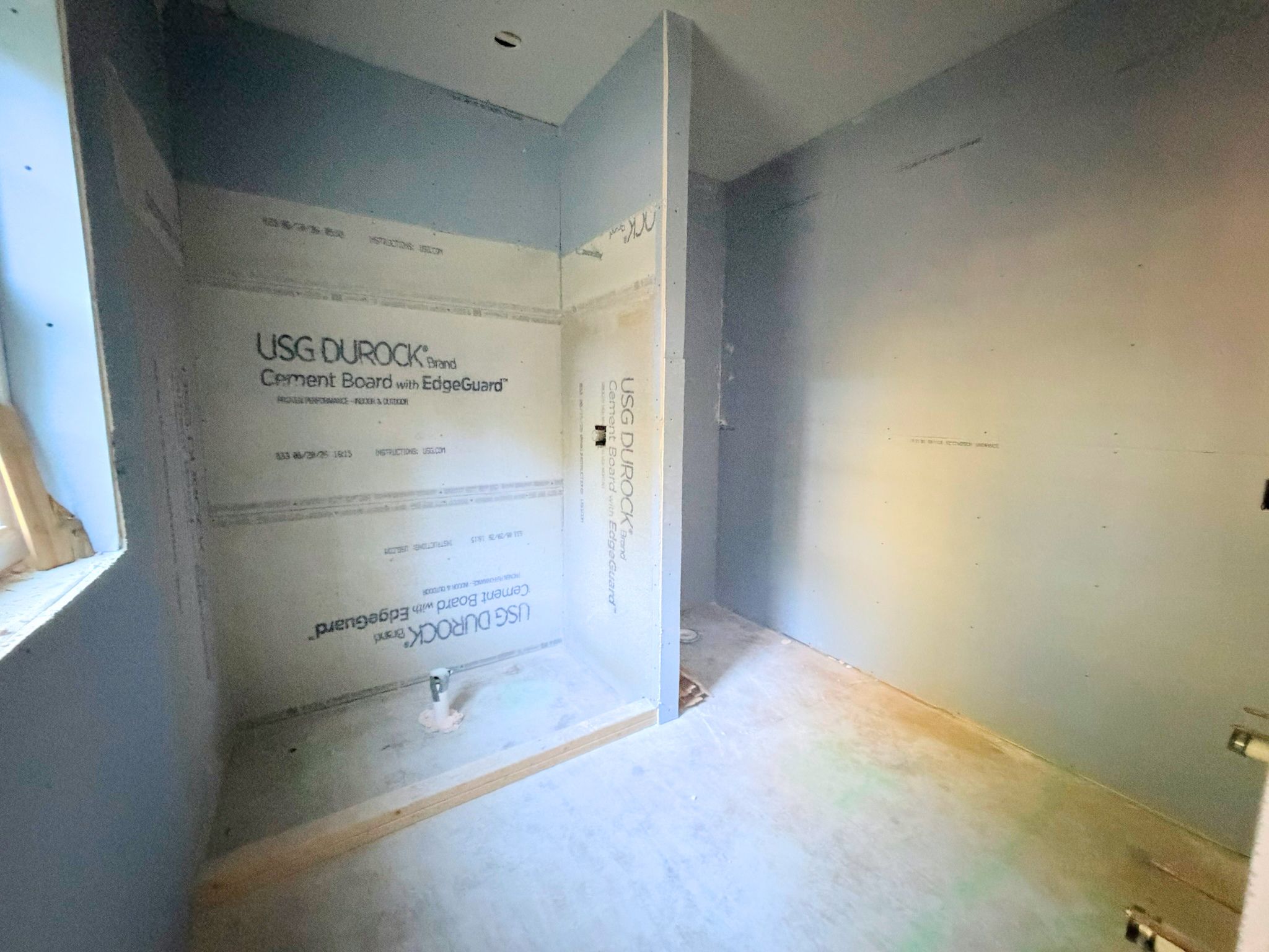 Lower level full bathroom construction progress view showing the shower area in place as interior finish work continues.
