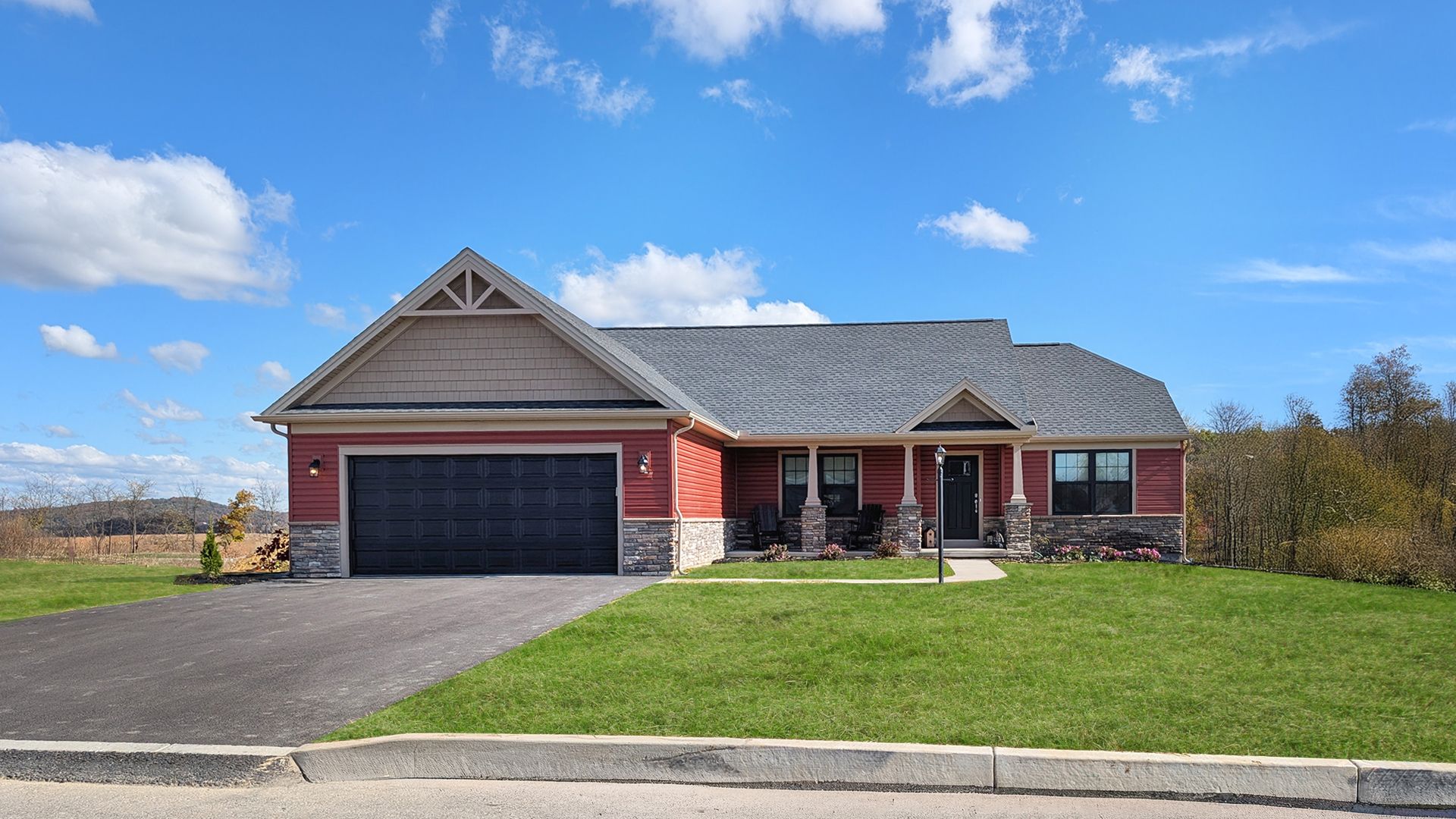 Red ranch-style Coleford home plan with stone accents, covered front porch, black garage door, and green lawn under a bright blue sky.