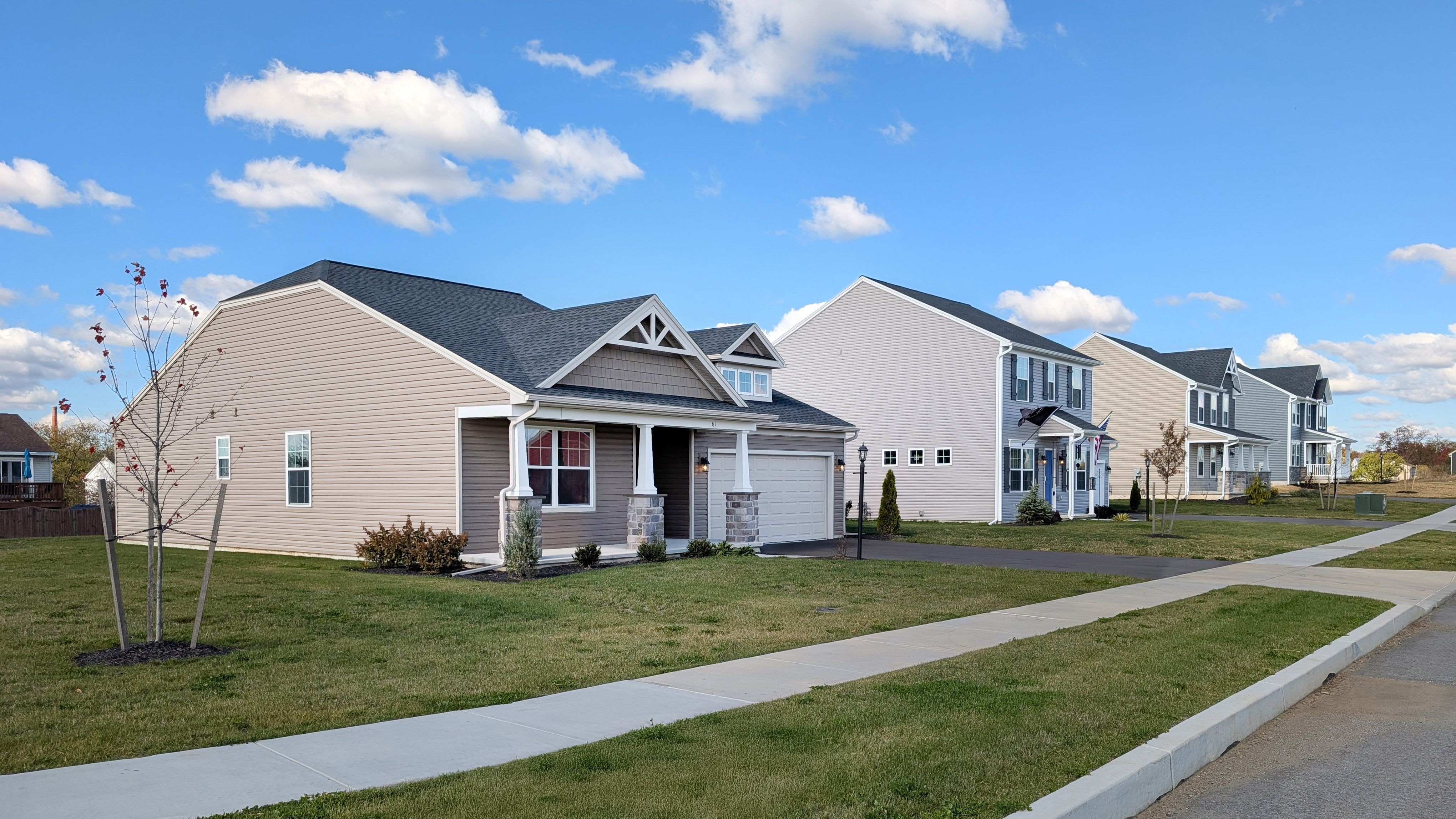 Streetscape of new S&A Homes in Appleview Estates featuring ranch and two-story homes with sidewalks, lawns, and a clear blue sky.