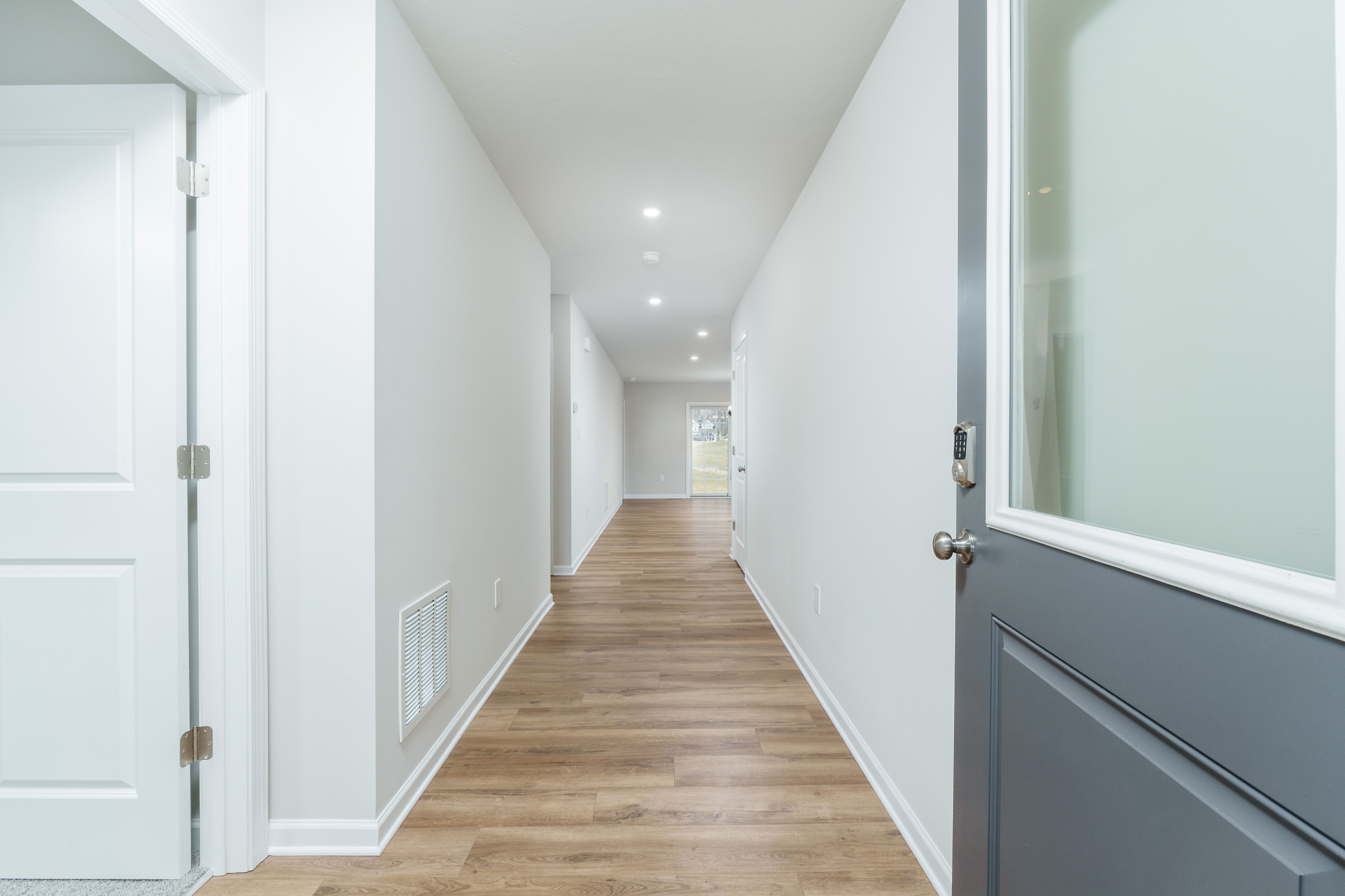 Long foyer hallway with luxury vinyl plank flooring, recessed ceiling lights, and view toward rear sliding door