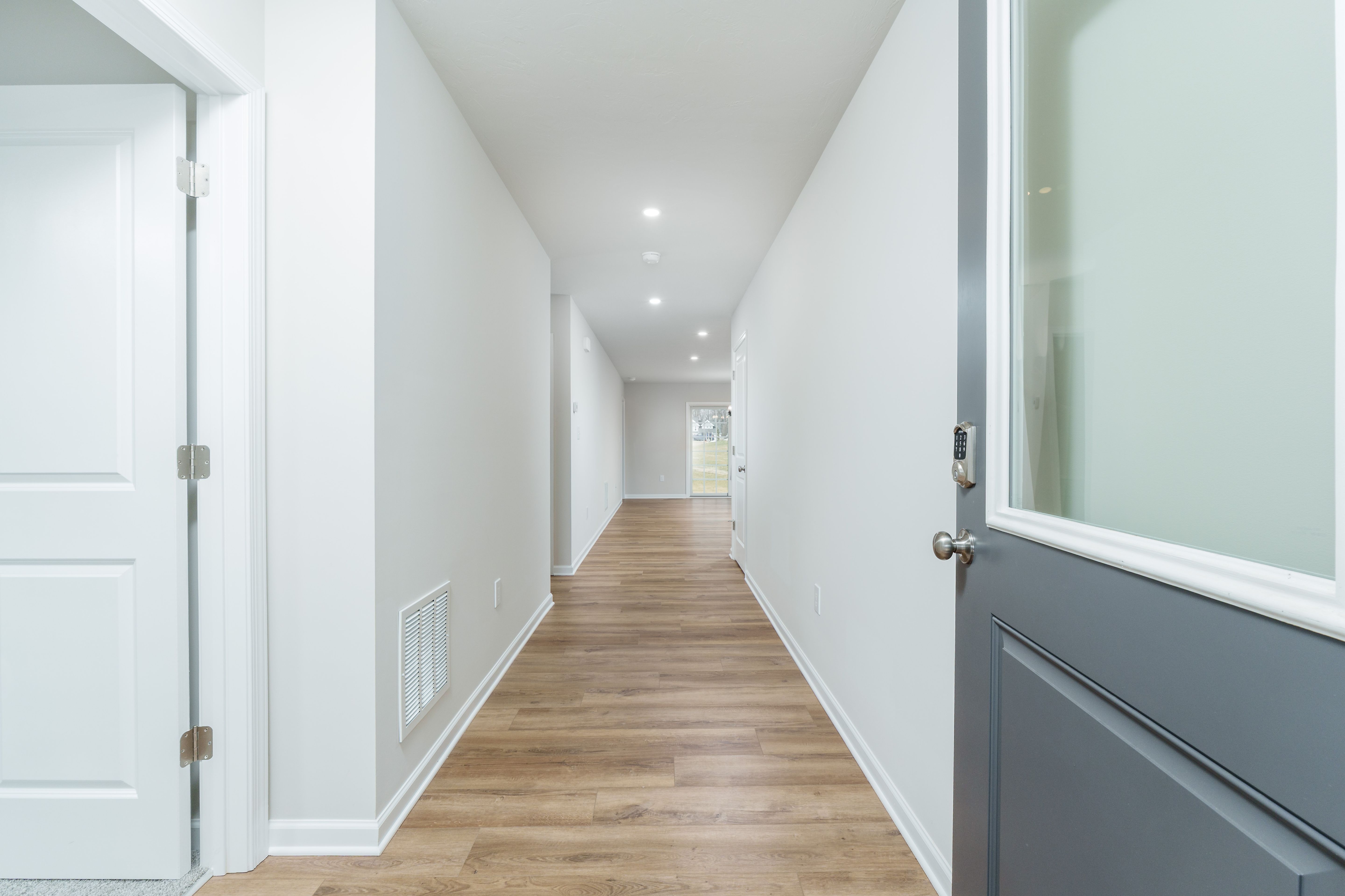 Long foyer hallway with luxury vinyl plank flooring, recessed ceiling lights, and view toward rear sliding door