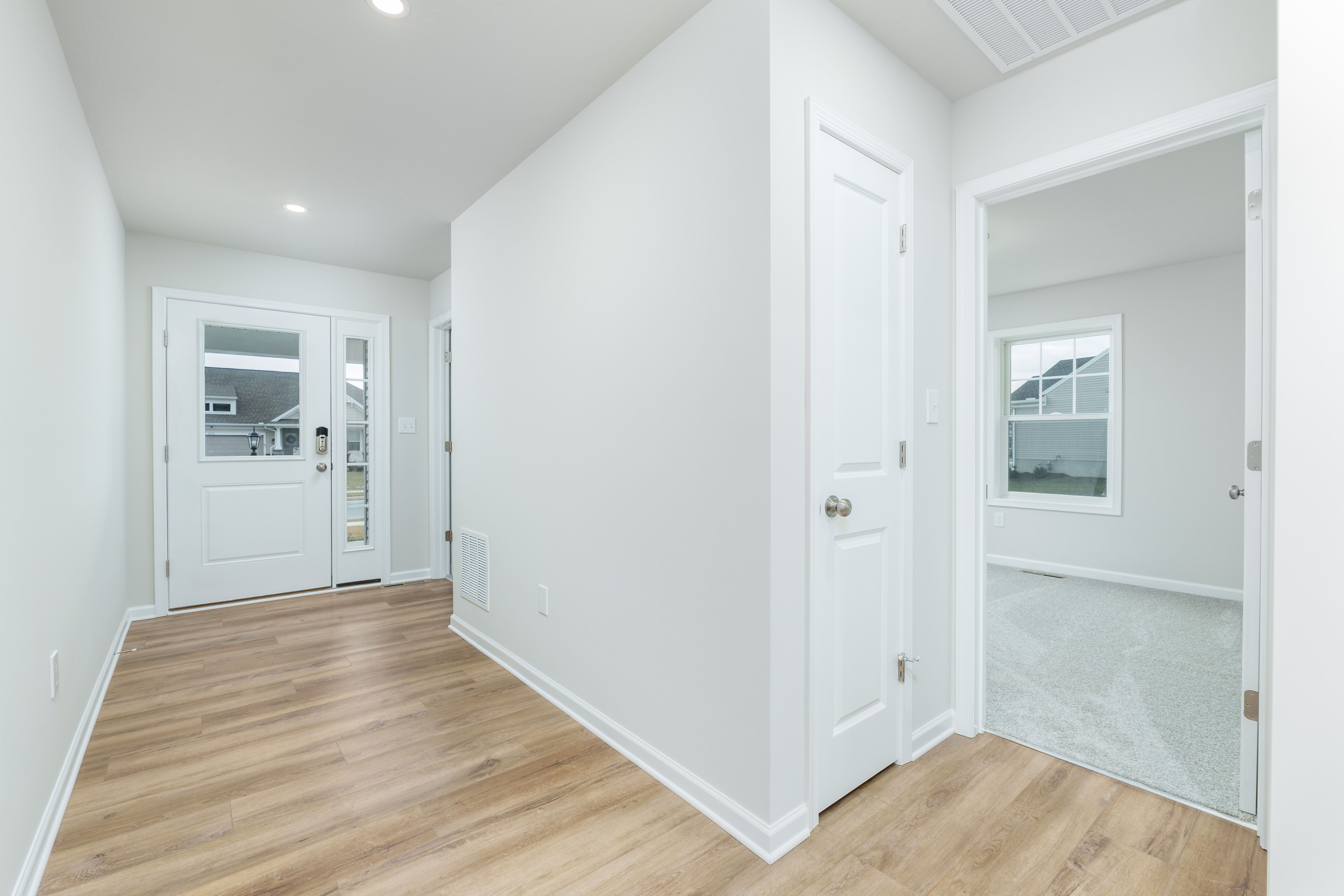 Alternate foyer angle with luxury vinyl plank flooring, front entry door, and nearby interior room access
