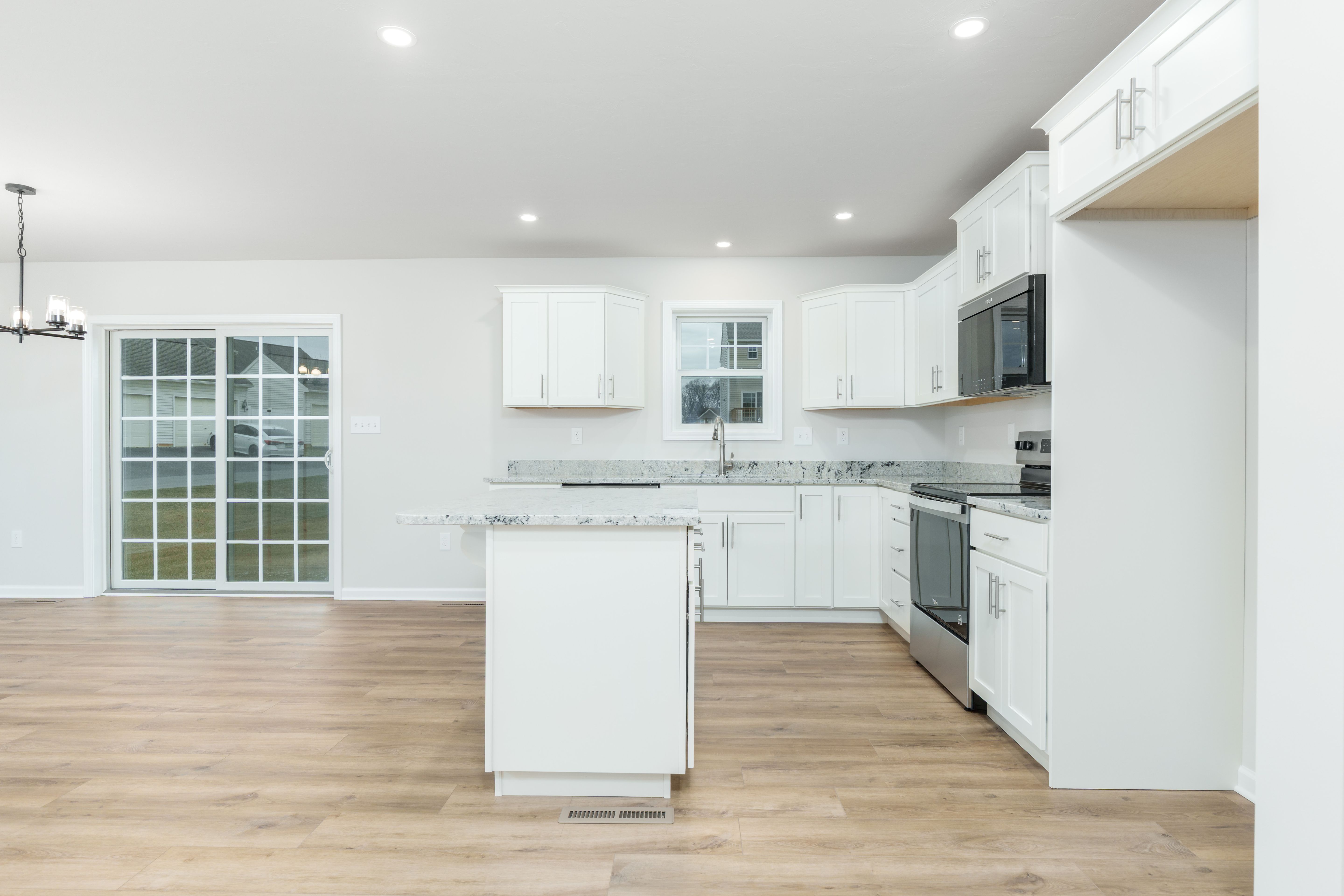 Bright kitchen with center island, white cabinetry, stainless appliances, recessed lighting, and luxury vinyl plank flooring