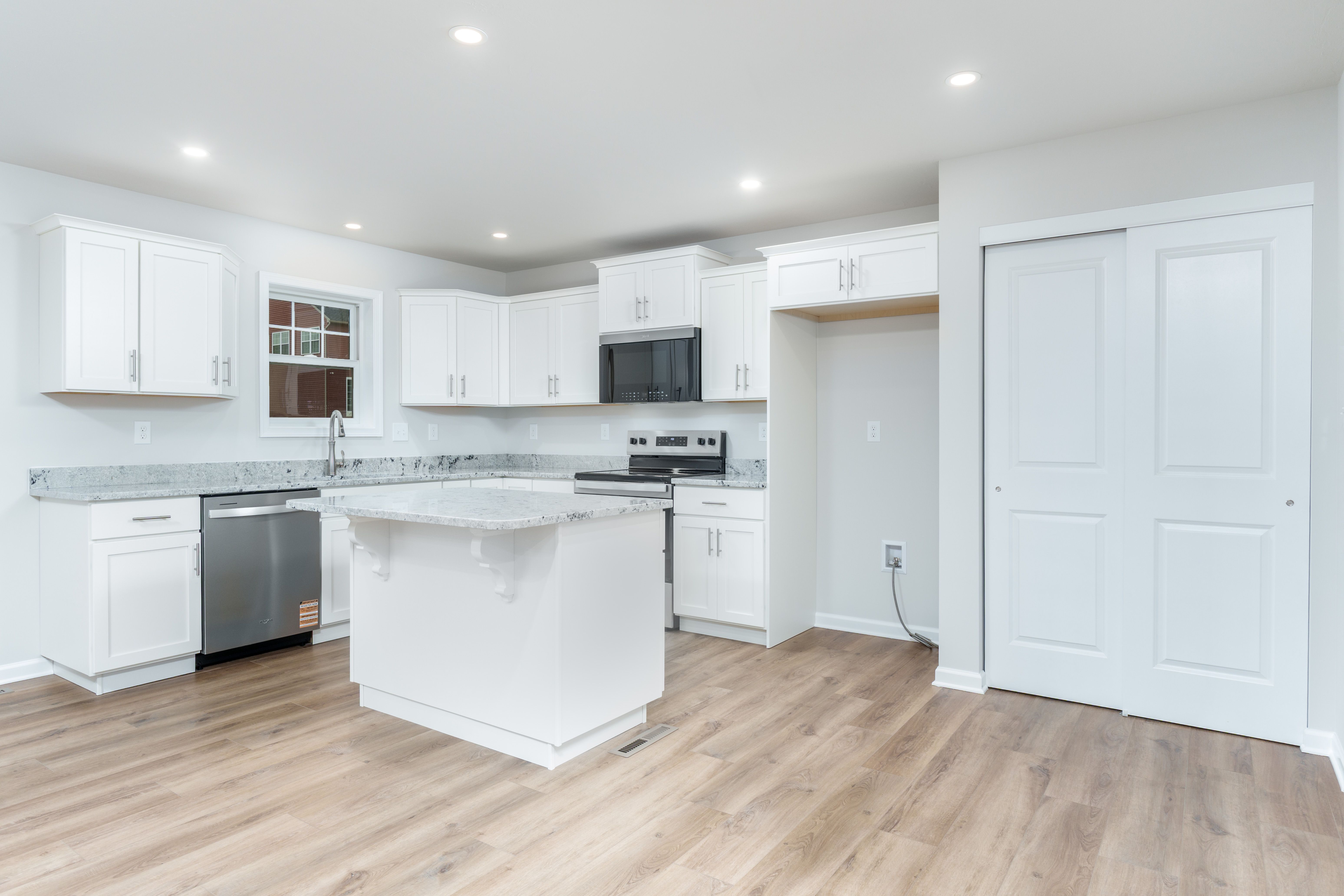 Kitchen with island, stainless appliances, pantry area, recessed lighting, and luxury vinyl plank flooring