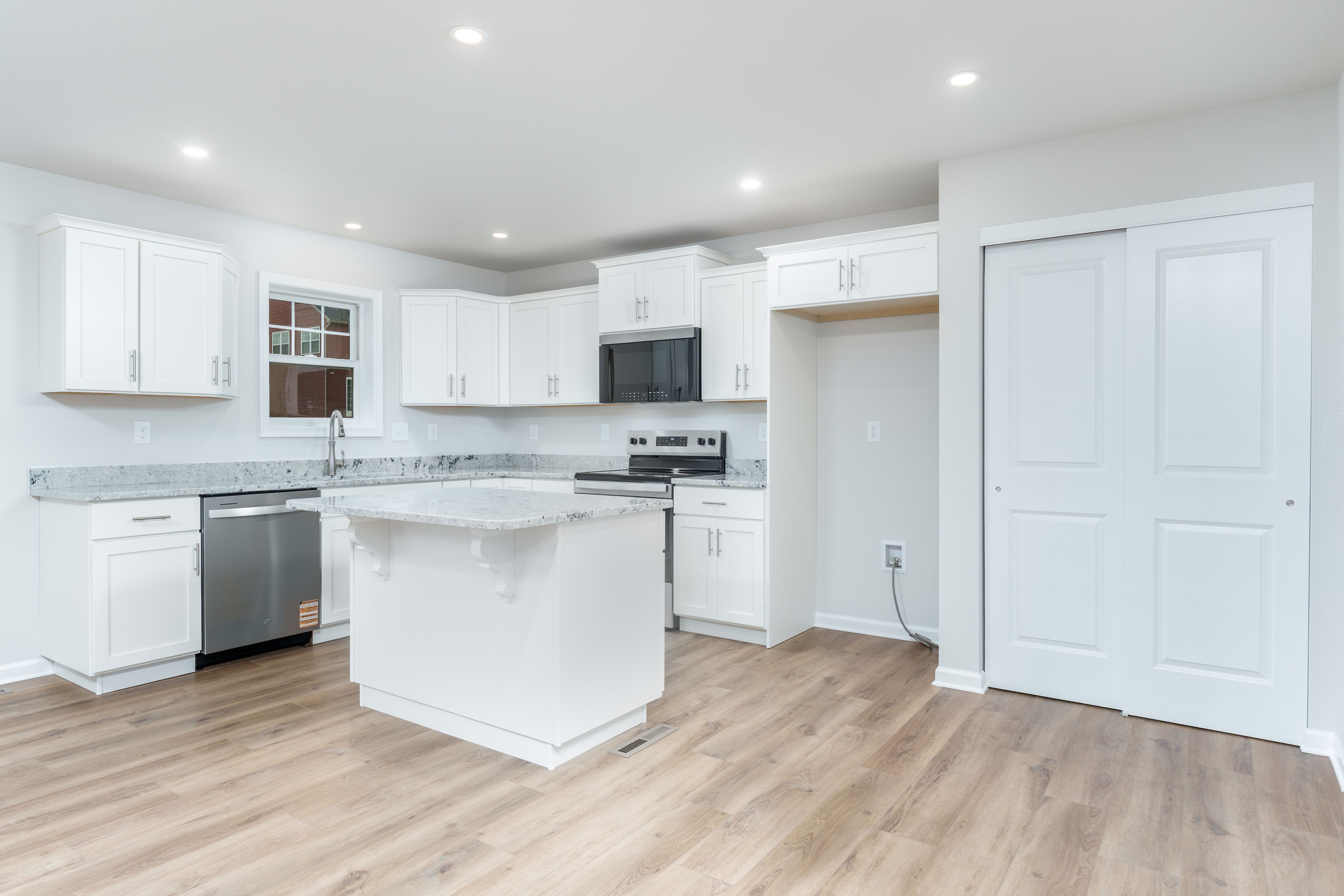 Kitchen with island, stainless appliances, pantry area, recessed lighting, and luxury vinyl plank flooring