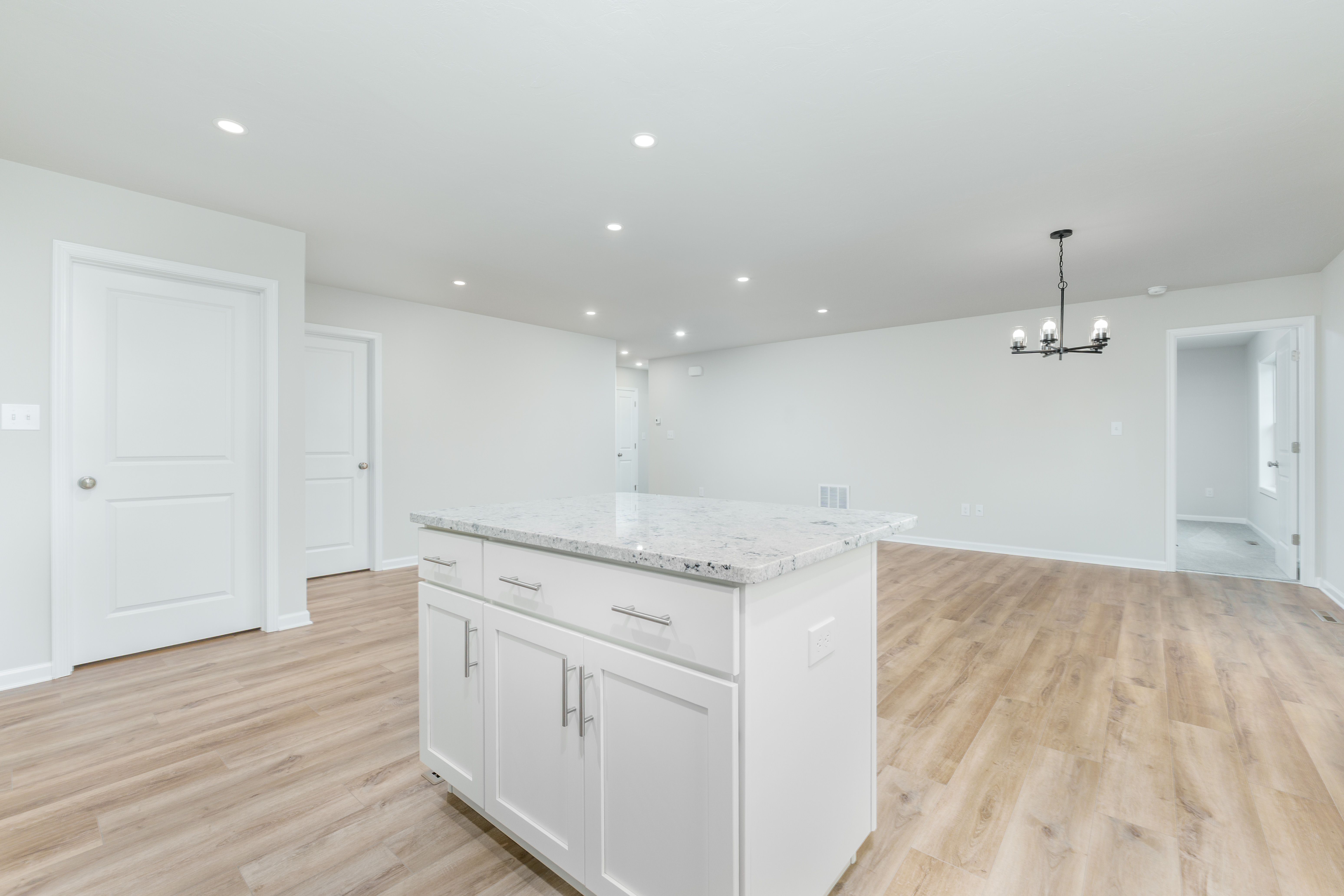 Kitchen island with light countertop overlooking open living and dining space with luxury vinyl plank flooring