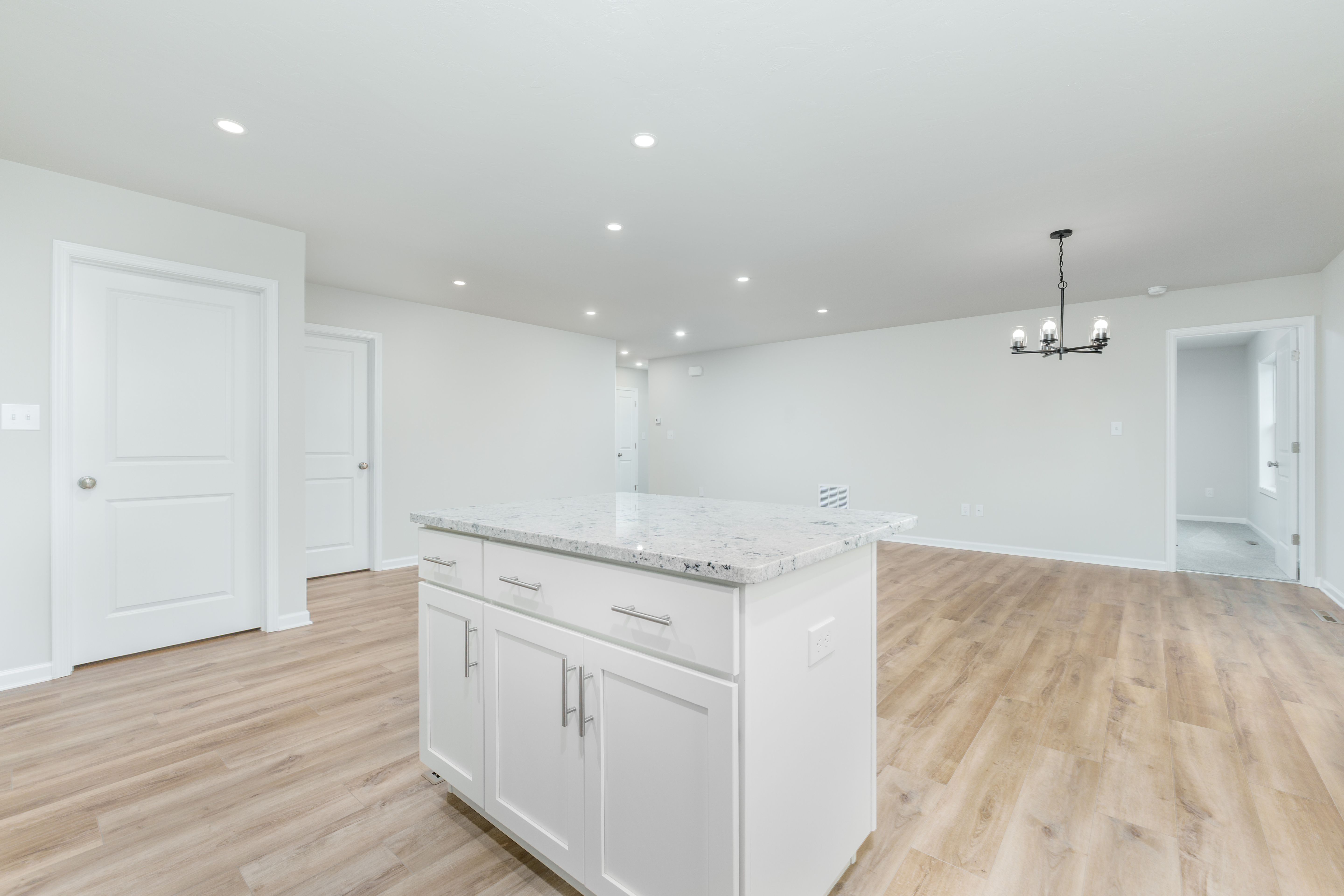 Kitchen island with light countertop overlooking open living and dining space with luxury vinyl plank flooring