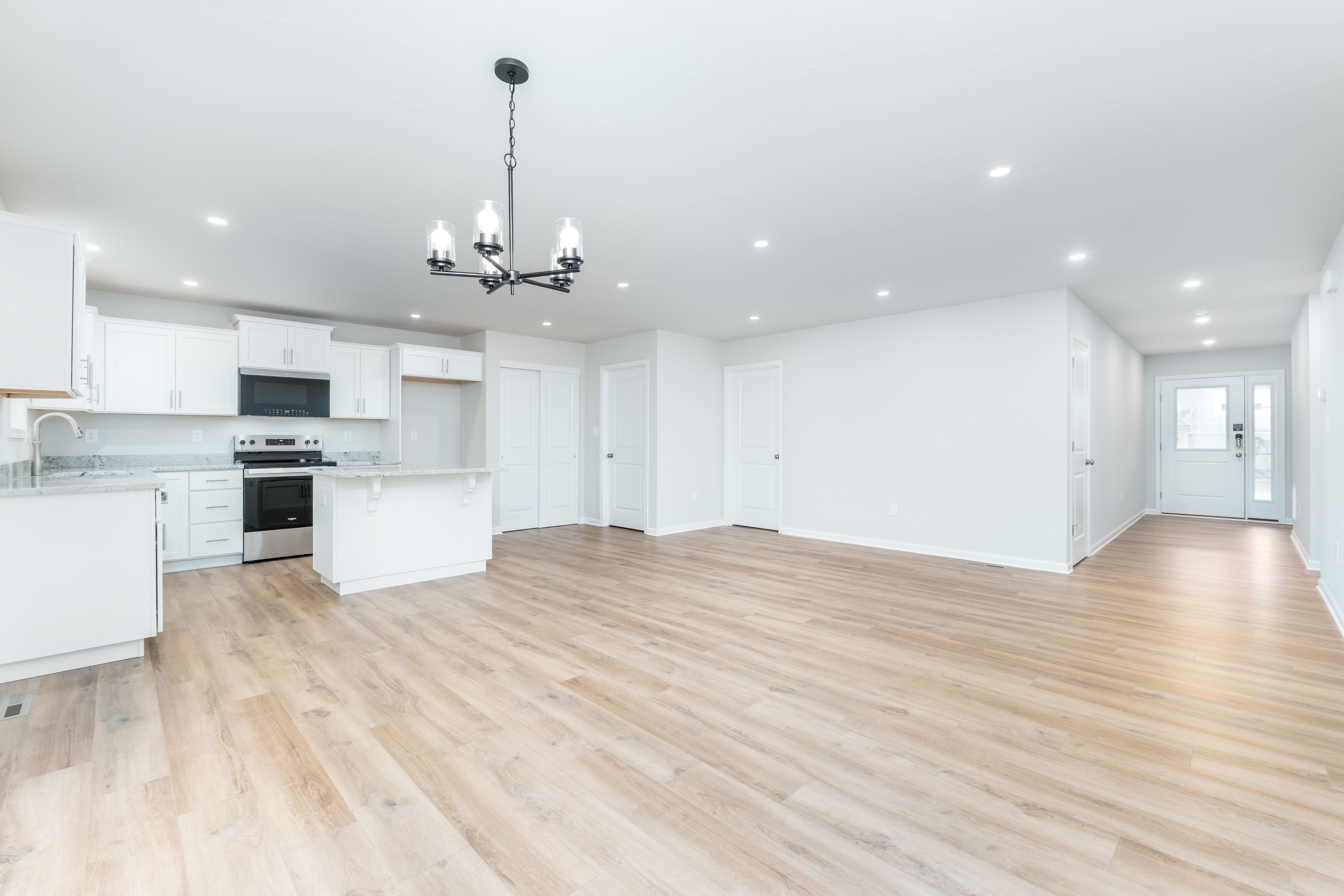 Wide view of kitchen and dining area featuring white cabinetry, island seating, chandelier, and open layout