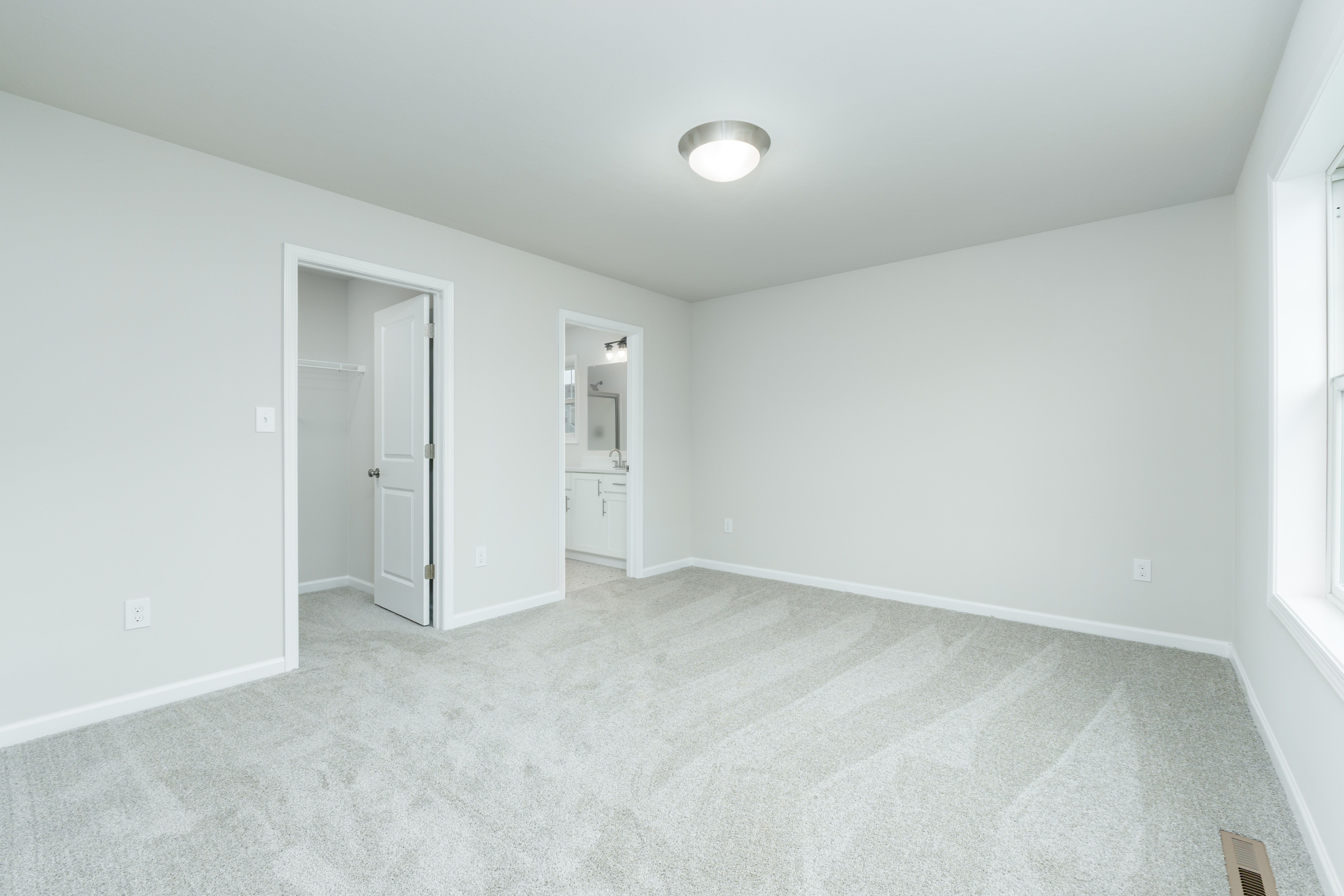 Owners bedroom with carpeted flooring, neutral walls, and doorway to attached bathroom
