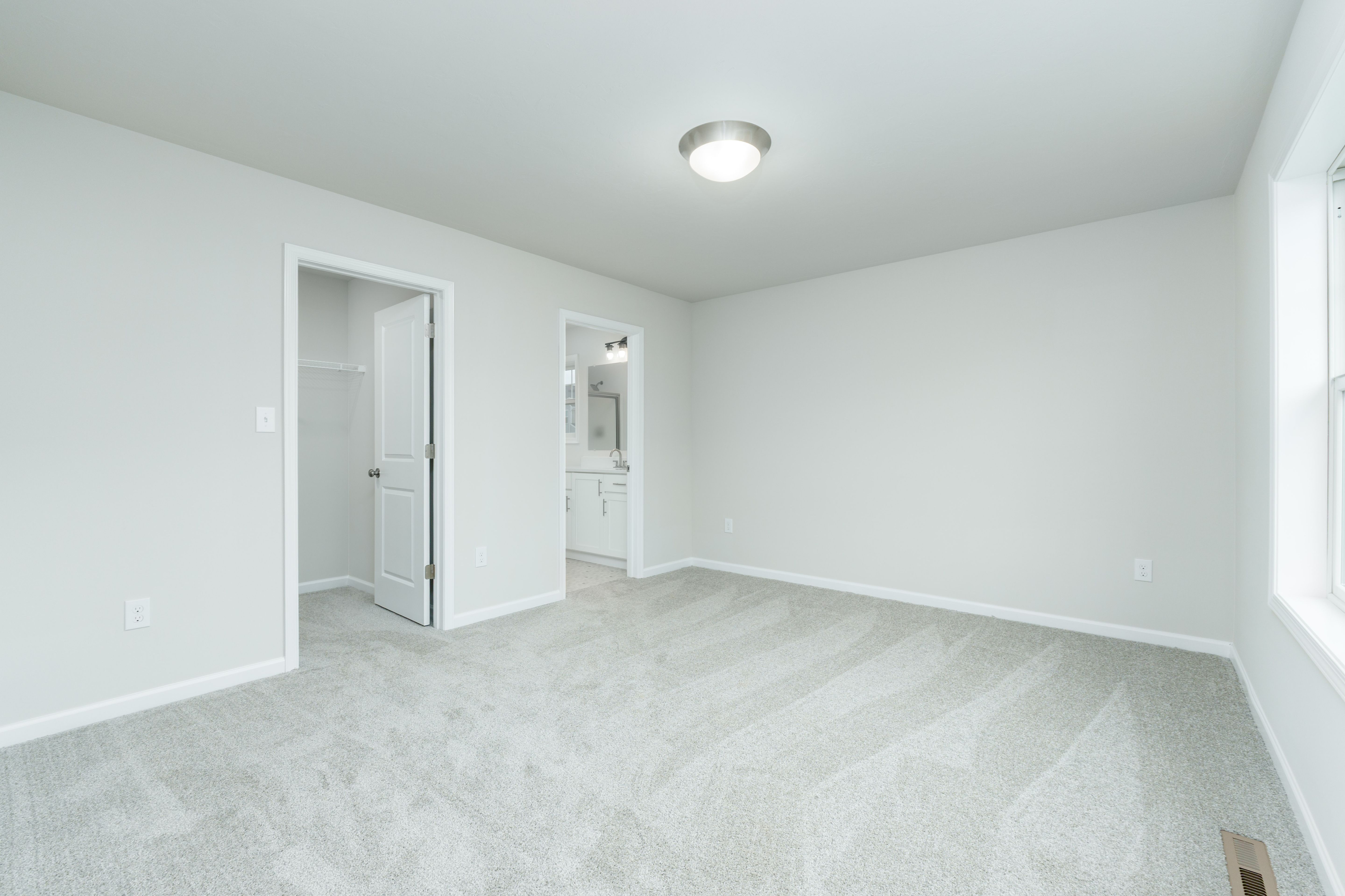 Owners bedroom with carpeted flooring, neutral walls, and doorway to attached bathroom