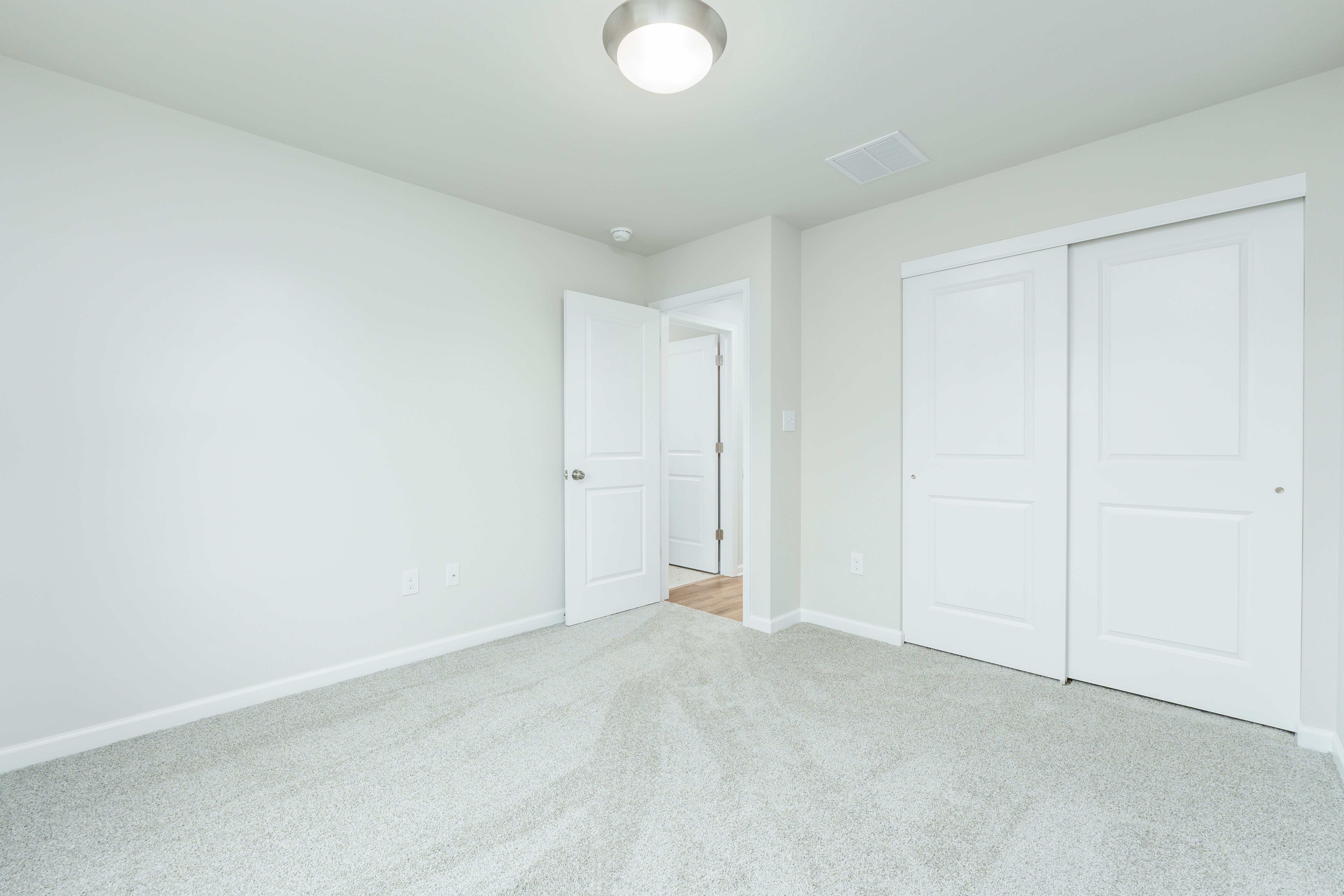 Bedroom featuring carpeted flooring, sliding closet doors, neutral walls, and ceiling light