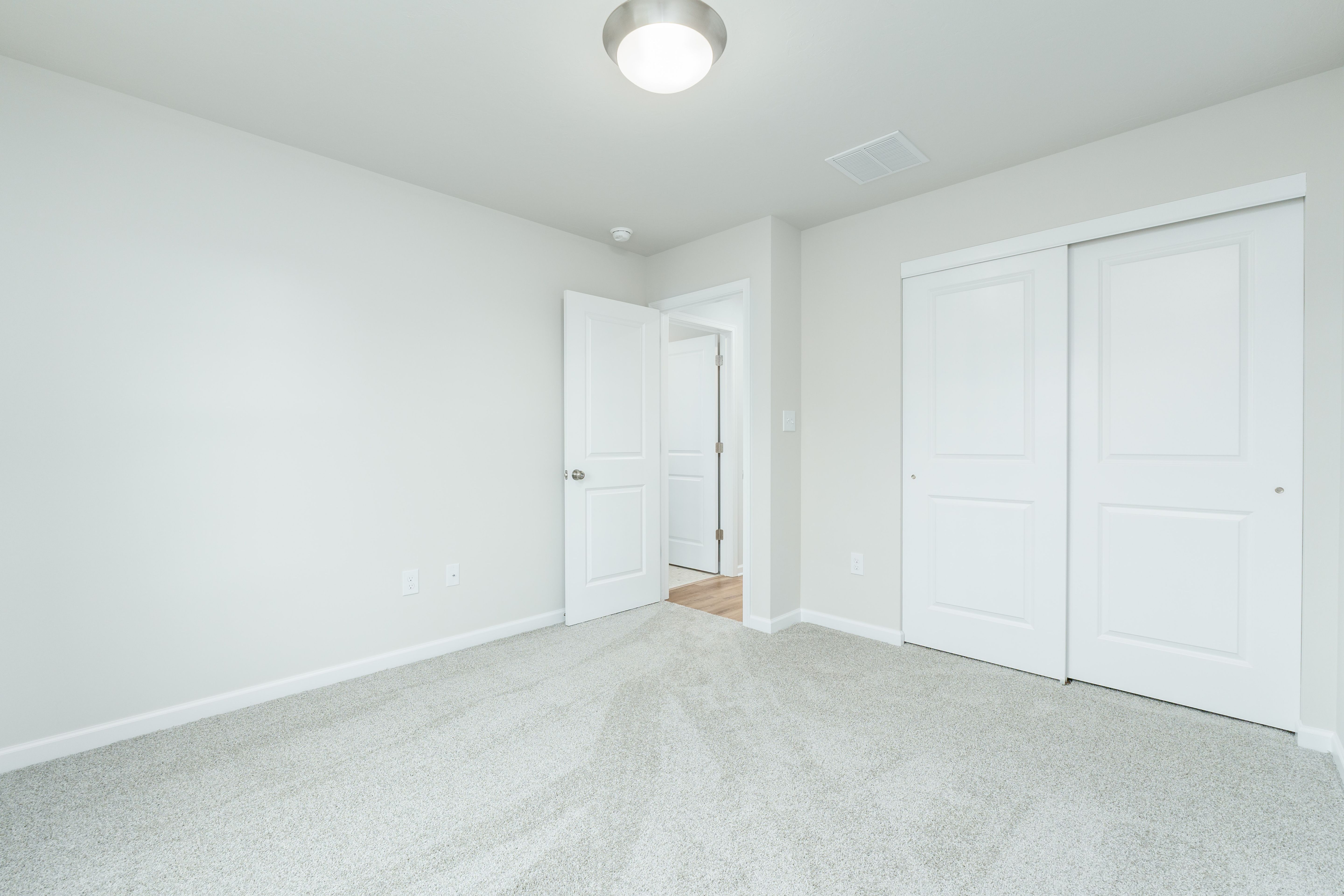 Bedroom featuring carpeted flooring, sliding closet doors, neutral walls, and ceiling light