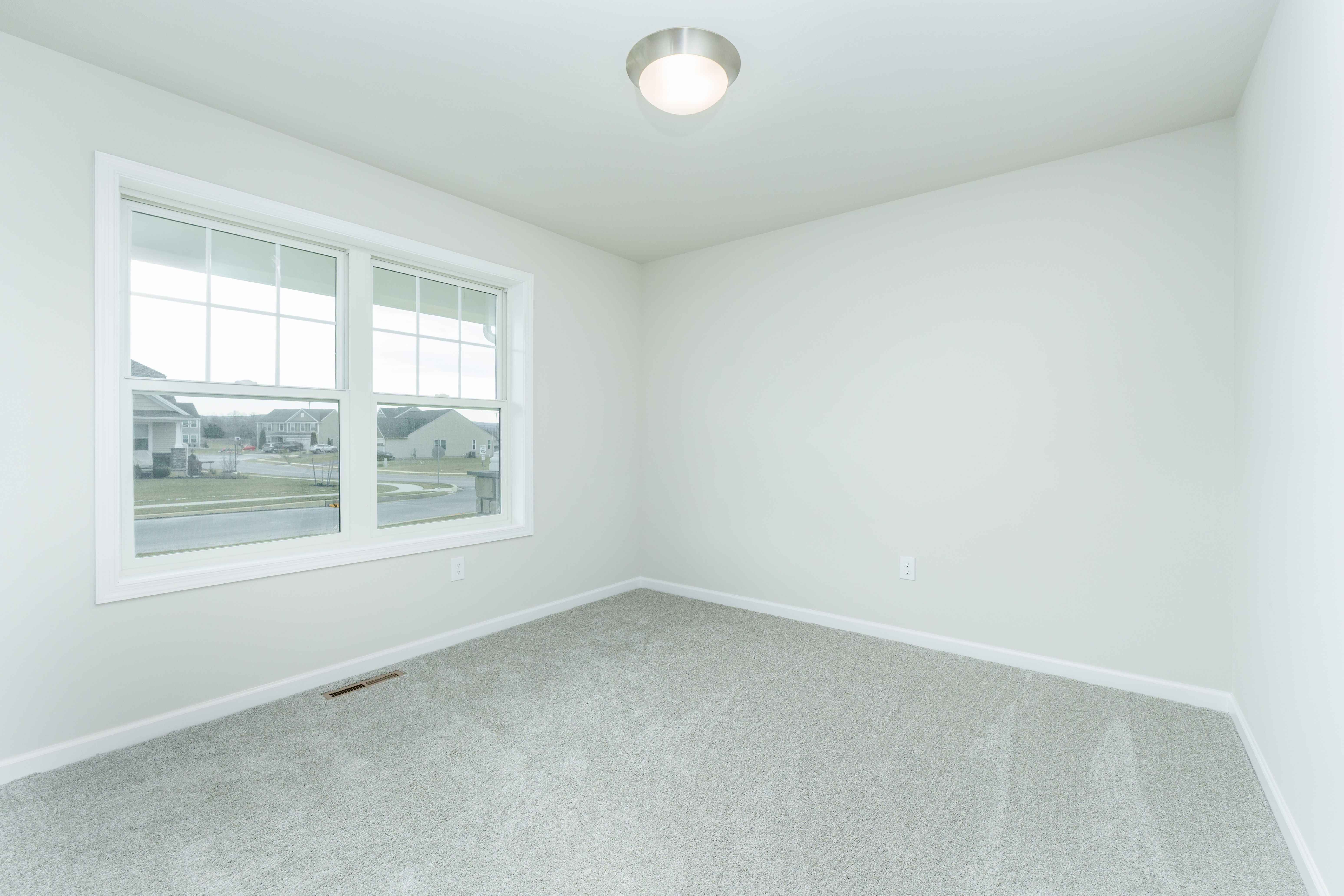 Bedroom with carpeted floor, large window for natural light, and soft neutral wall colors