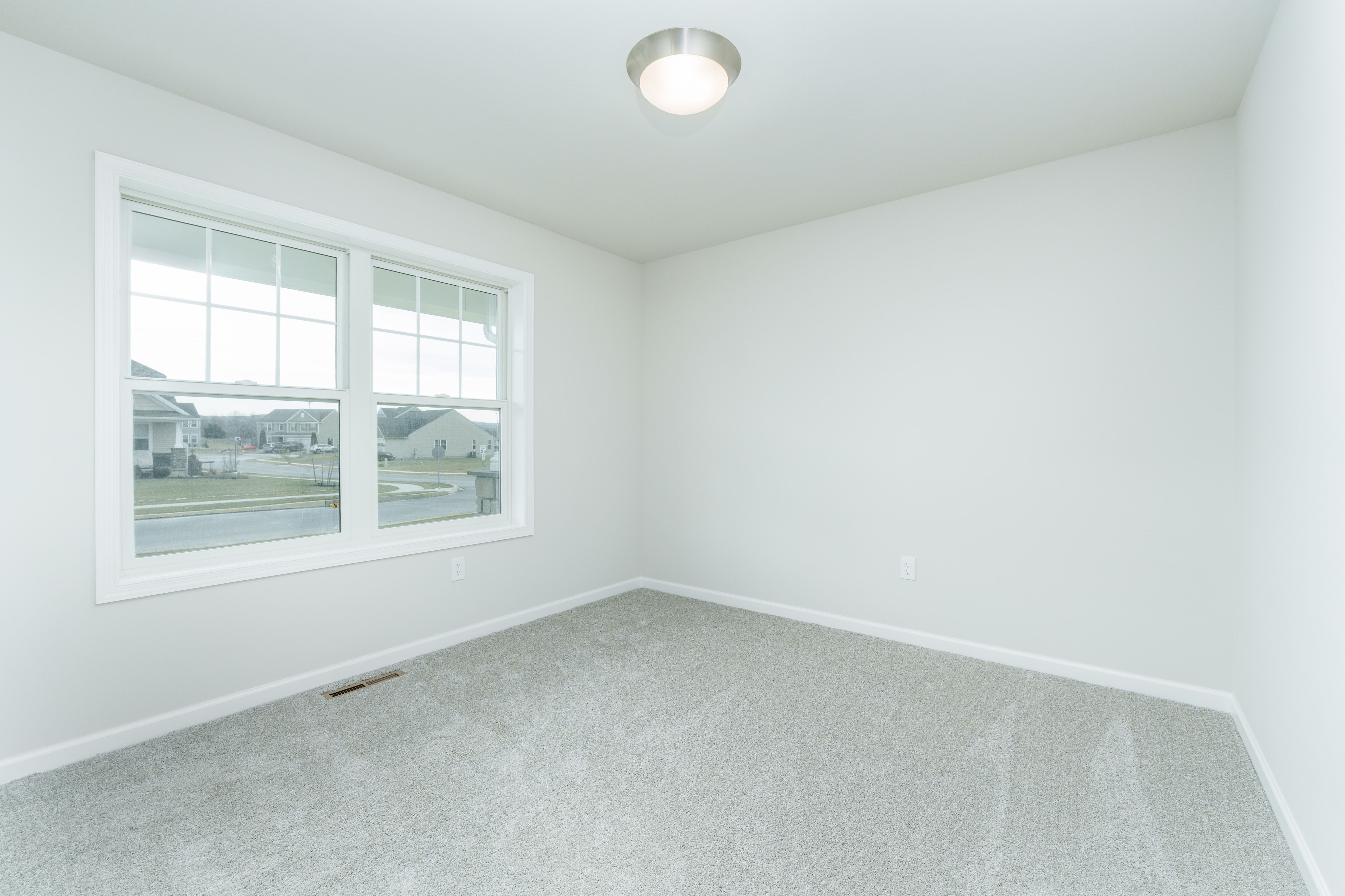Bedroom with carpeted floor, large window for natural light, and soft neutral wall colors