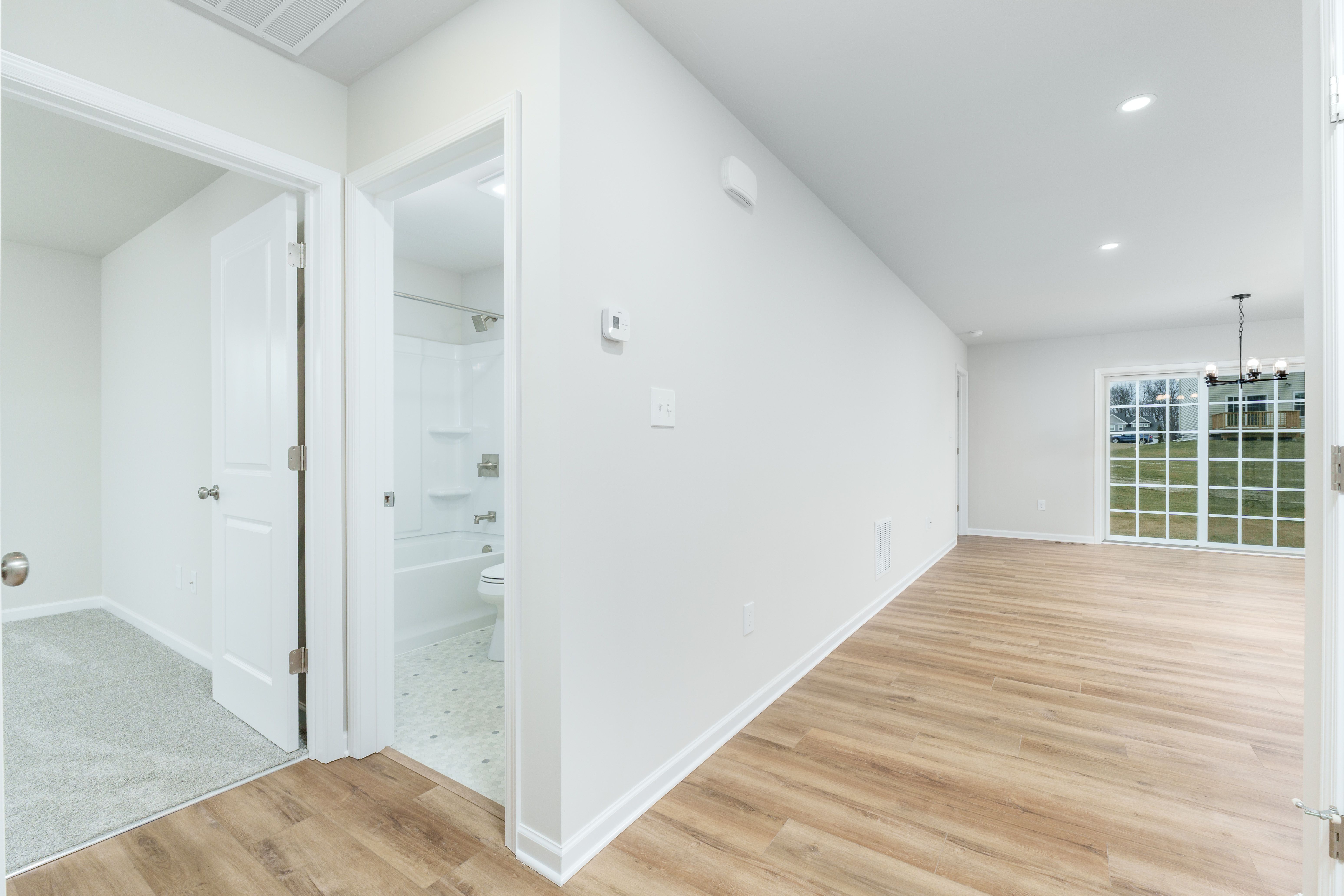 Hallway view showing bathroom entrance, luxury vinyl plank flooring, and sliding glass doors leading outside
