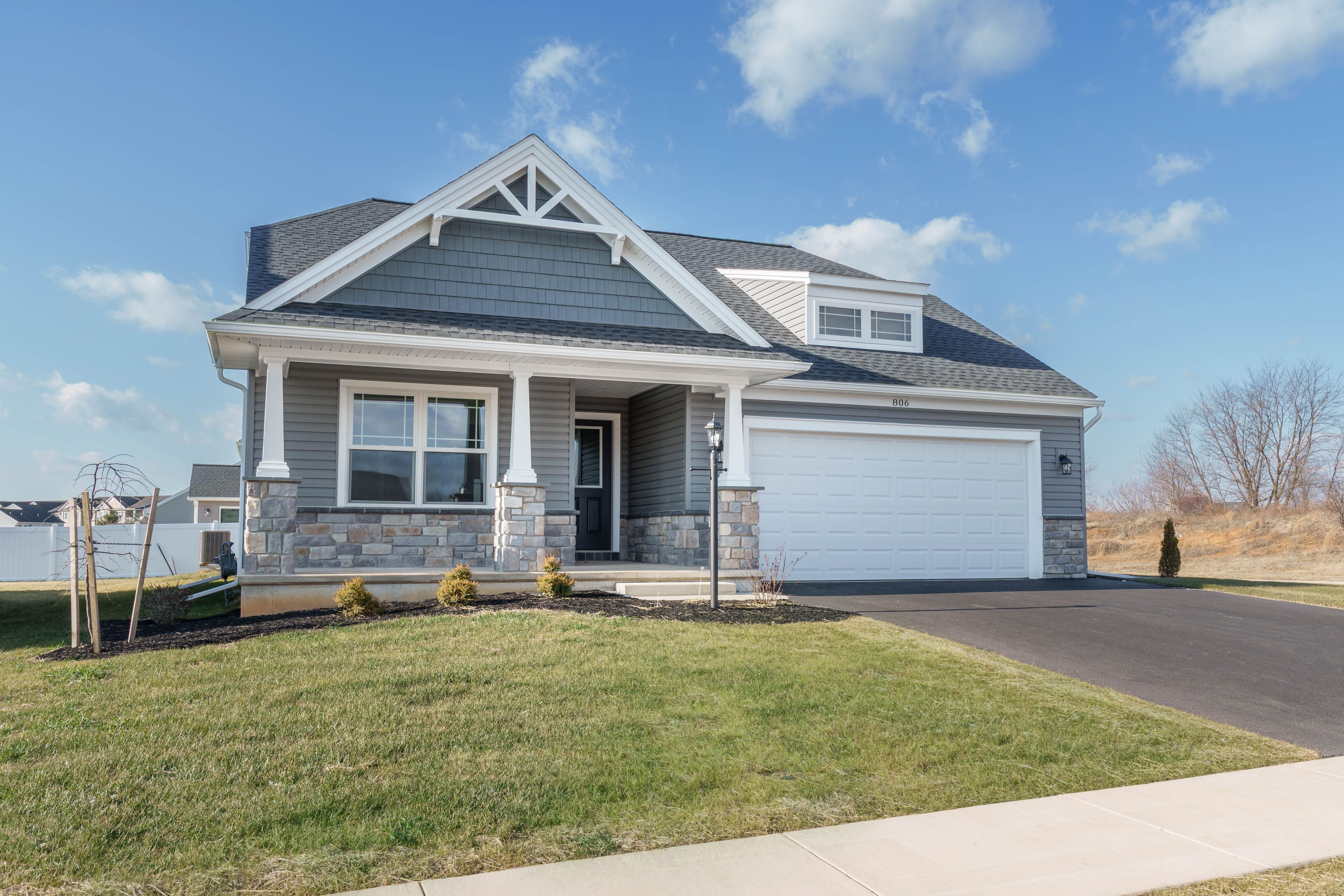 Gray ranch home with stone accents, covered front porch, and two-car garage in S&A Homes community