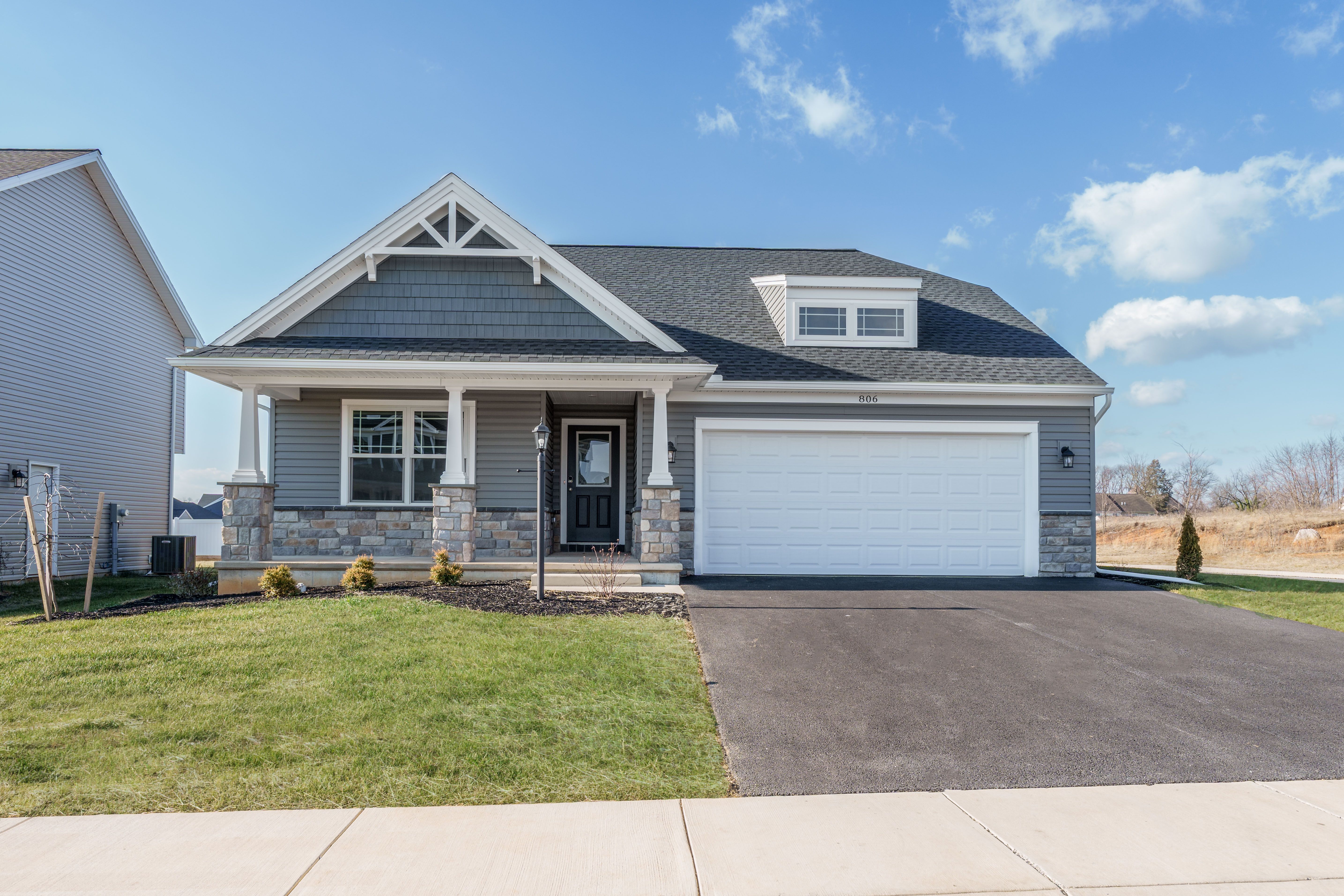 Front view of gray ranch with white trim, stone base, and attached two-car garage