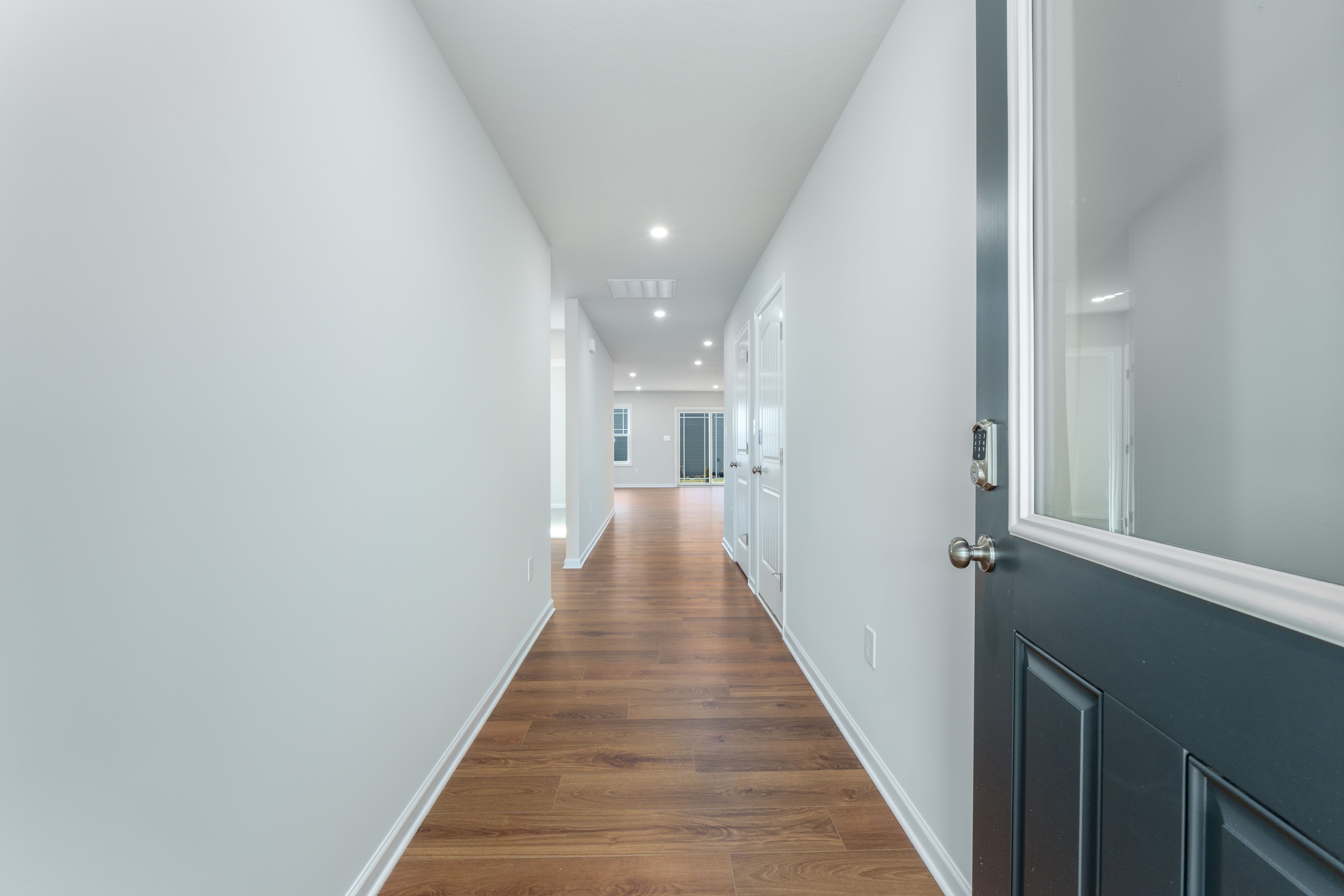 Long foyer with luxury vinyl plank flooring, recessed lights, and view toward open living area