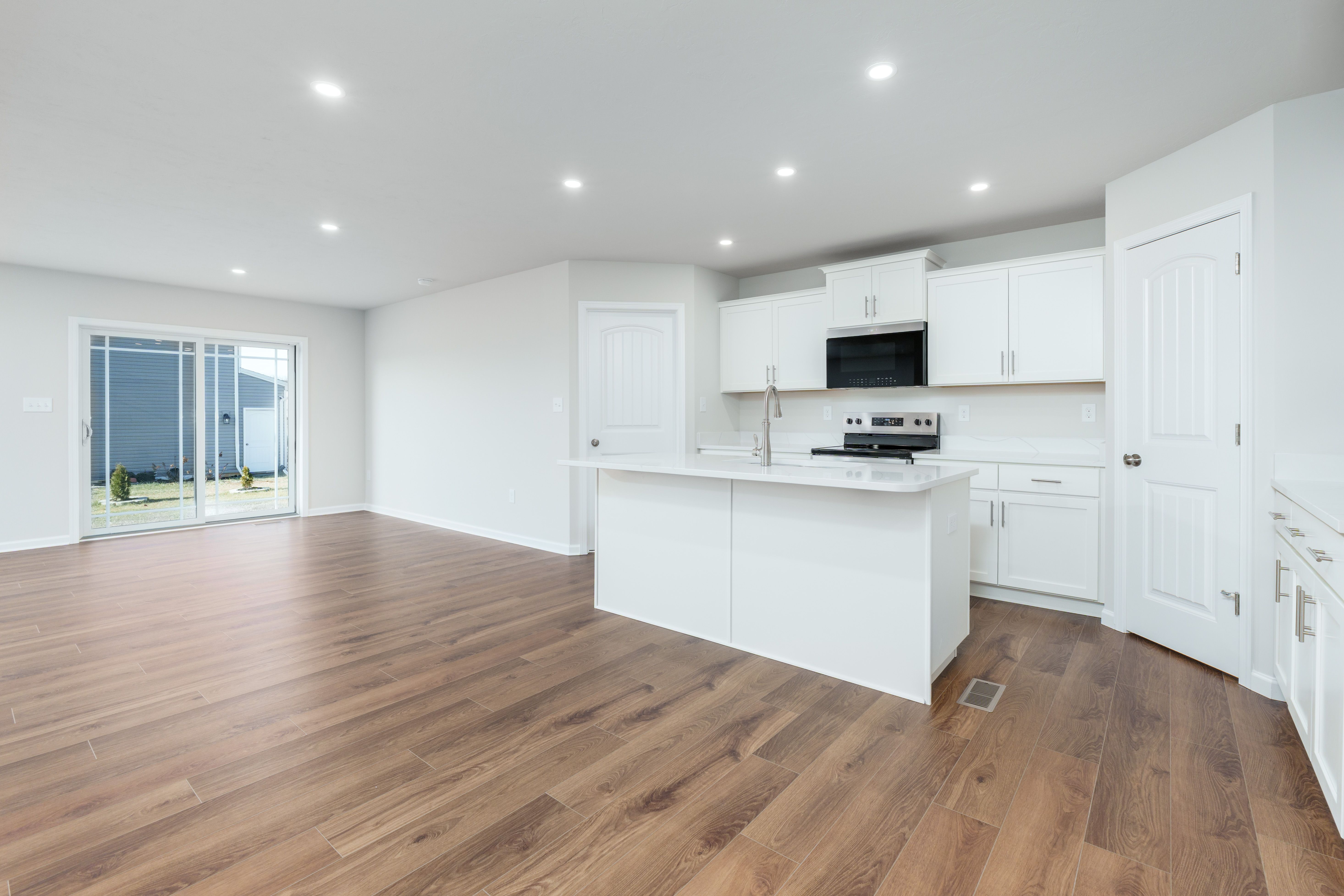 Bright kitchen with large island, stainless steel range, white cabinetry, and recessed lighting