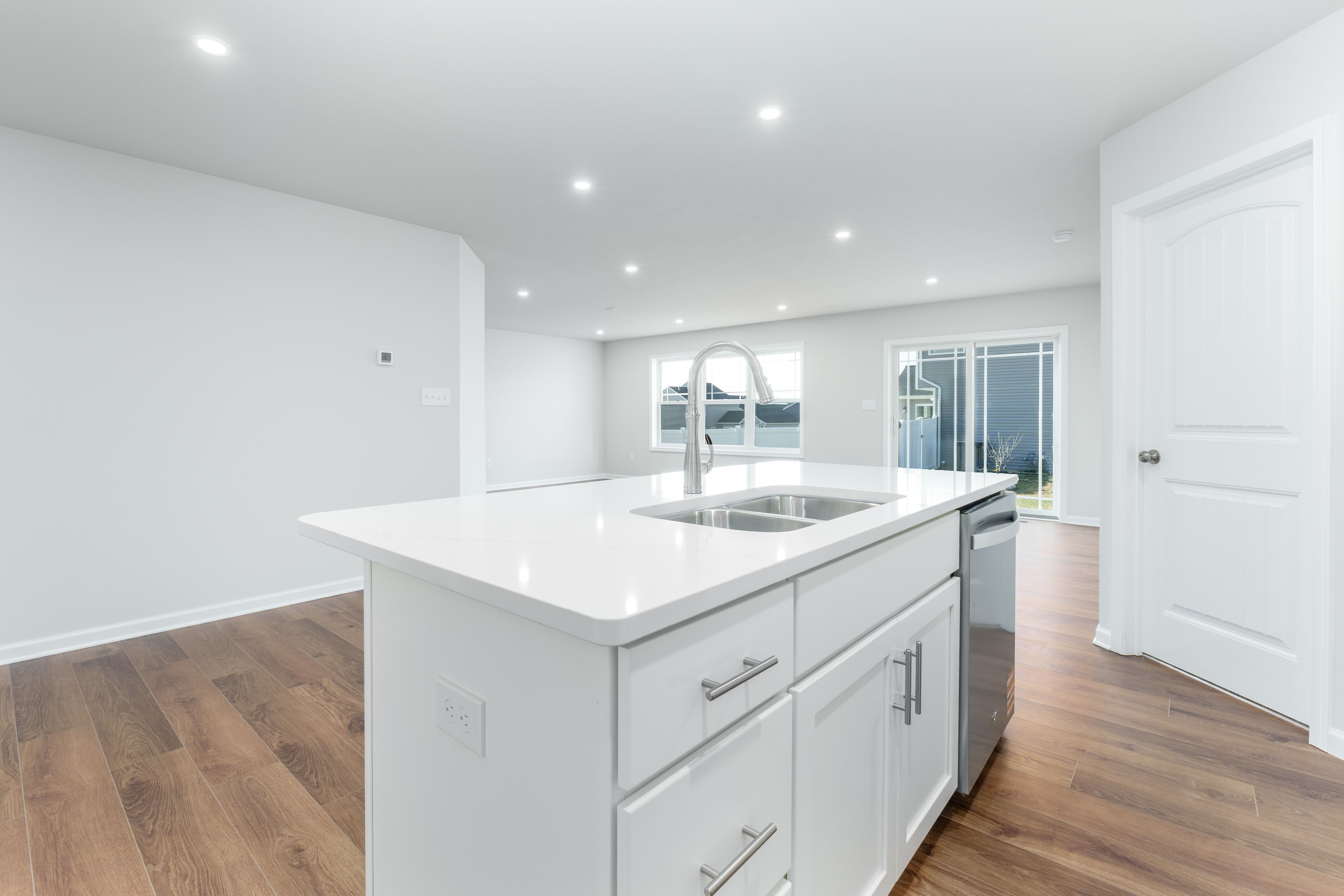 Kitchen island with double sink, white quartz countertop, and stainless dishwasher