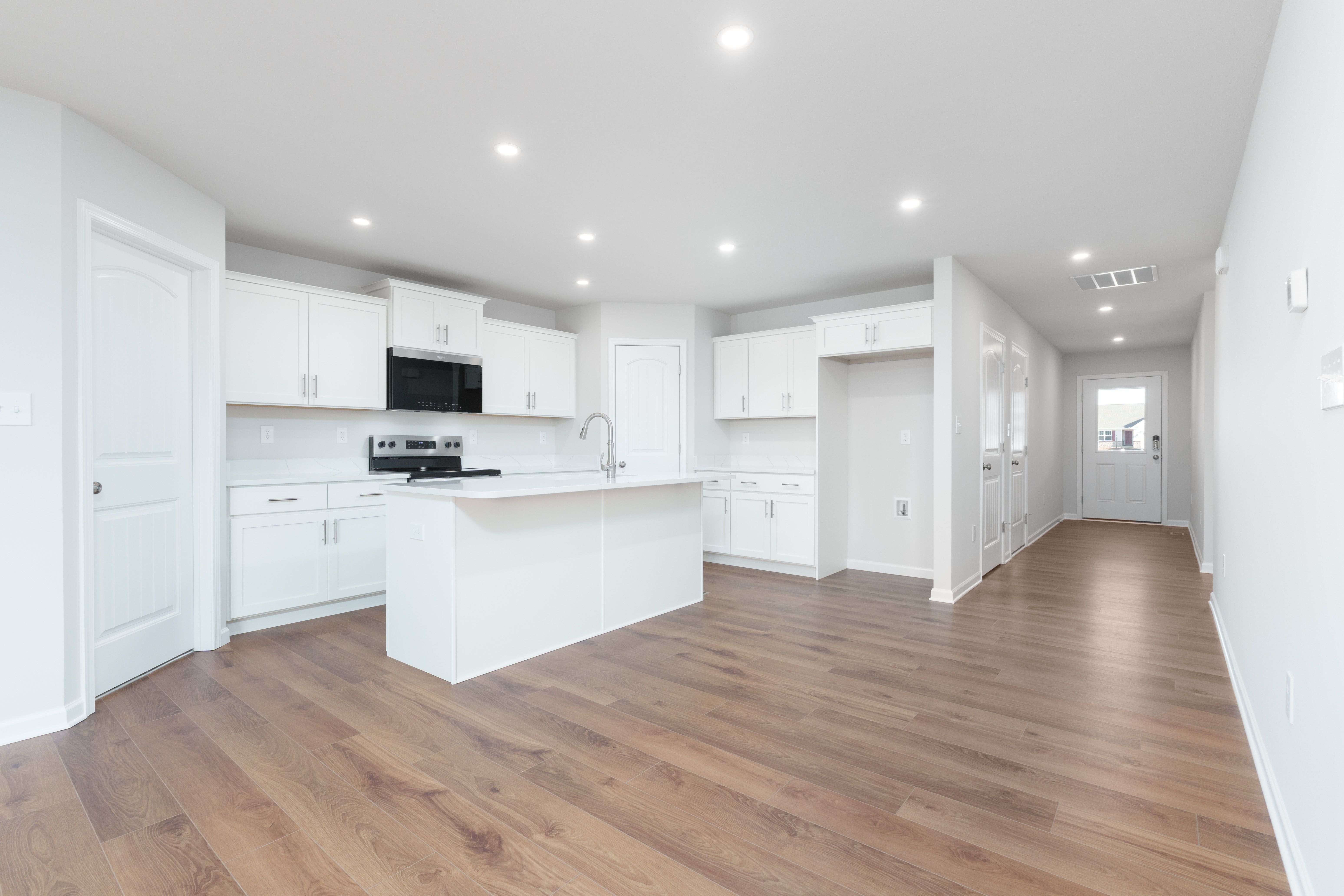 Modern kitchen with white cabinets, center island, stainless appliances, and luxury vinyl plank flooring