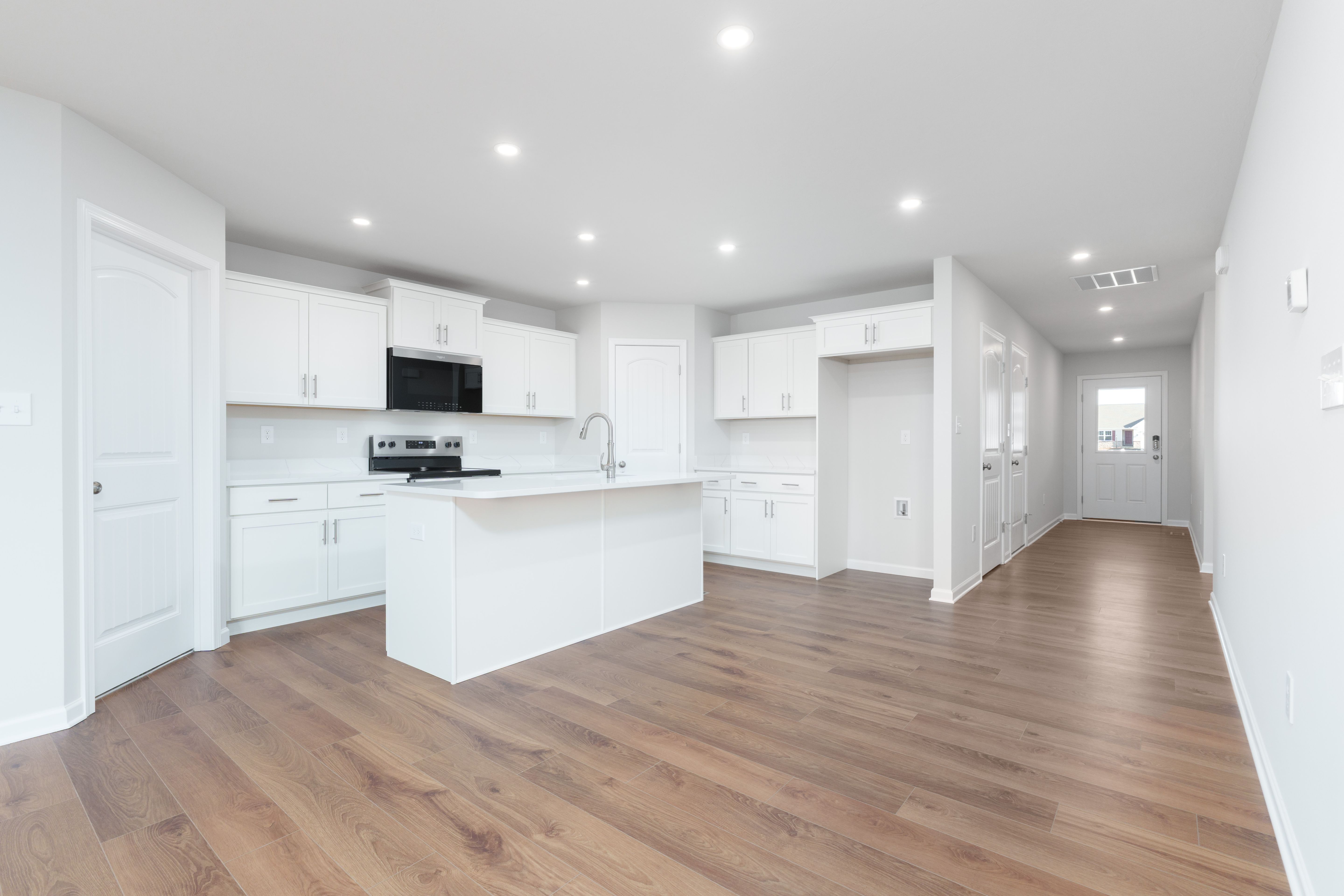 Modern kitchen with white cabinets, center island, stainless appliances, and luxury vinyl plank flooring