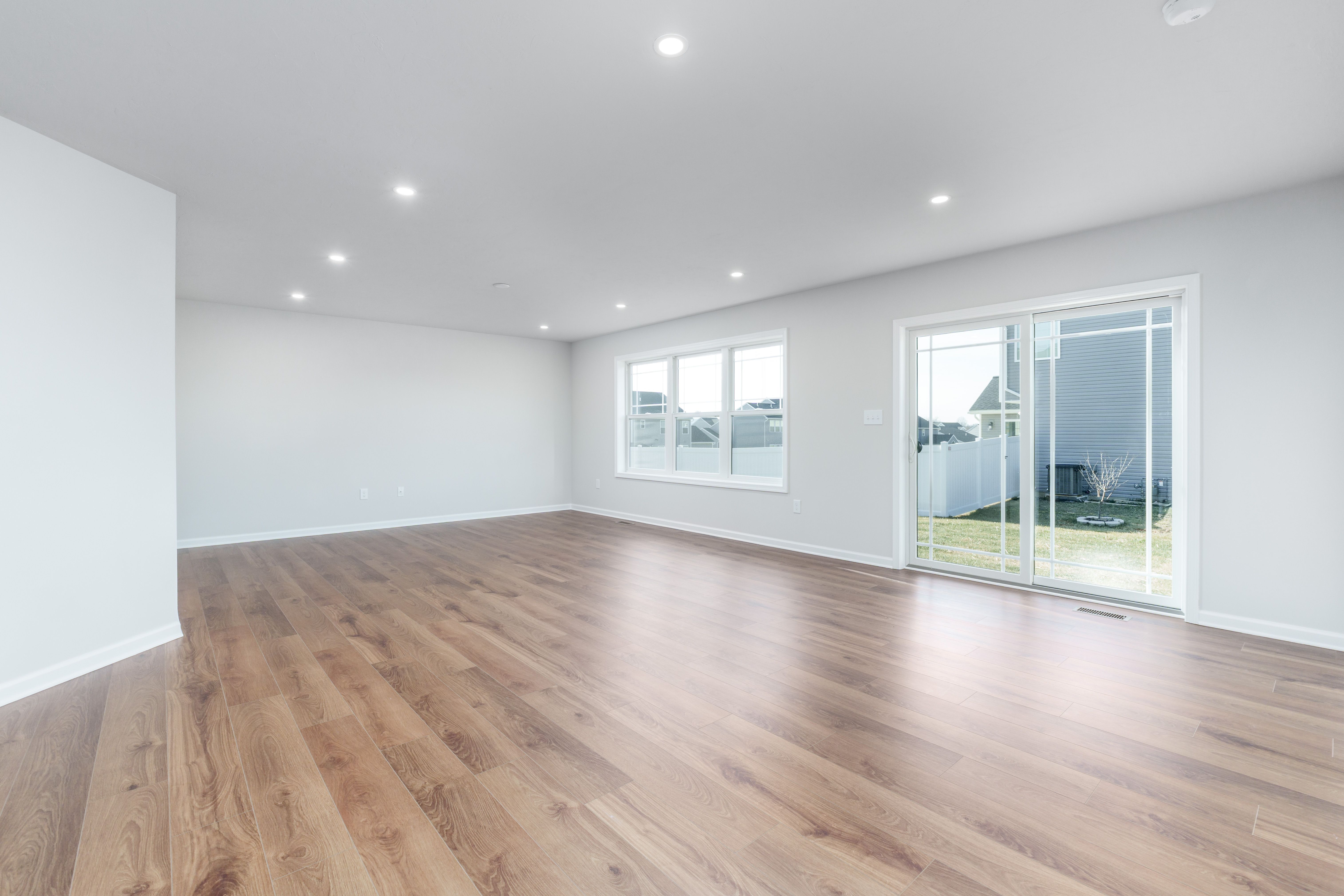 Great room with luxury vinyl plank flooring, recessed lighting, and sliding glass door to backyard