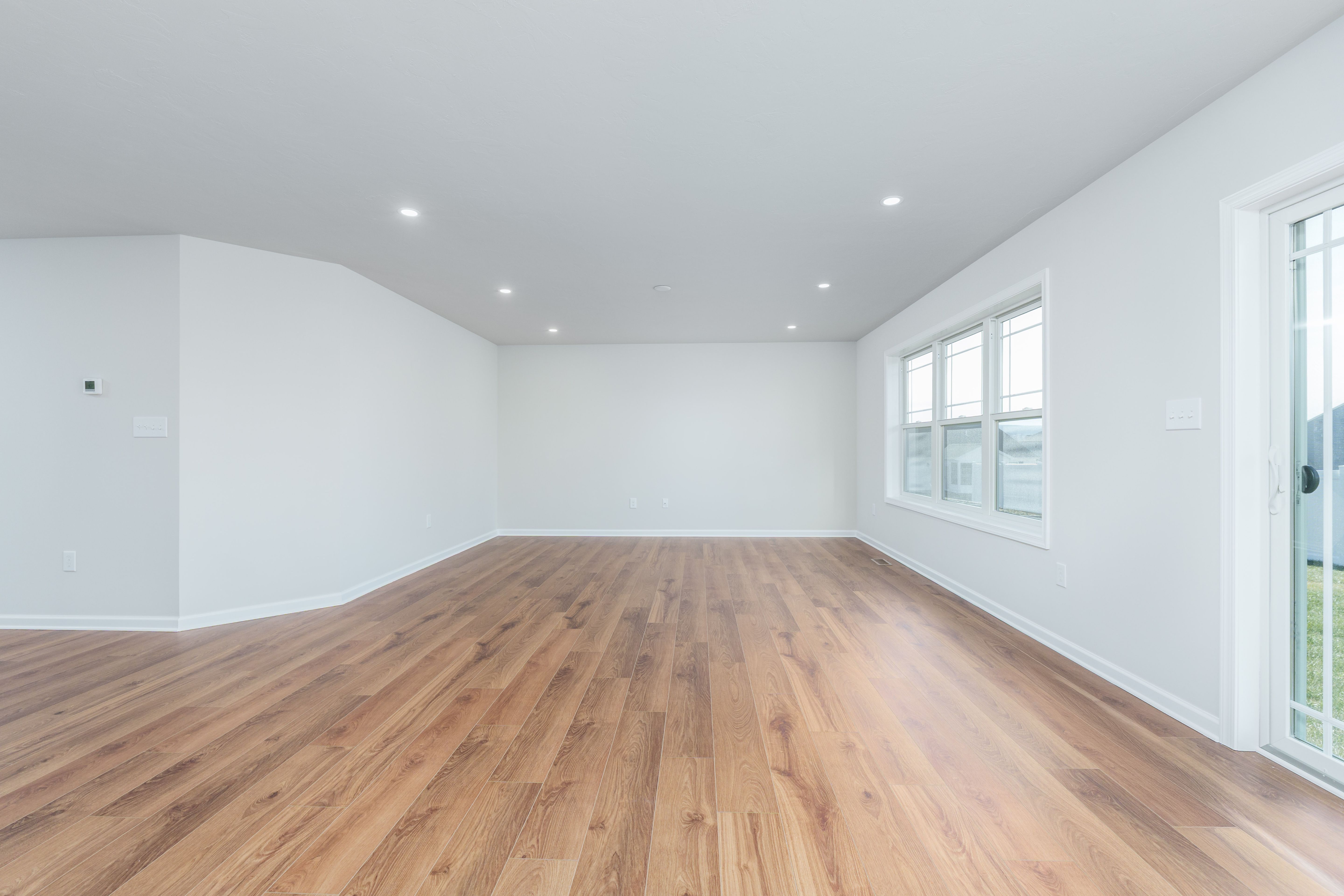 Open great room with wide plank luxury vinyl plank flooring, large windows, and bright natural light