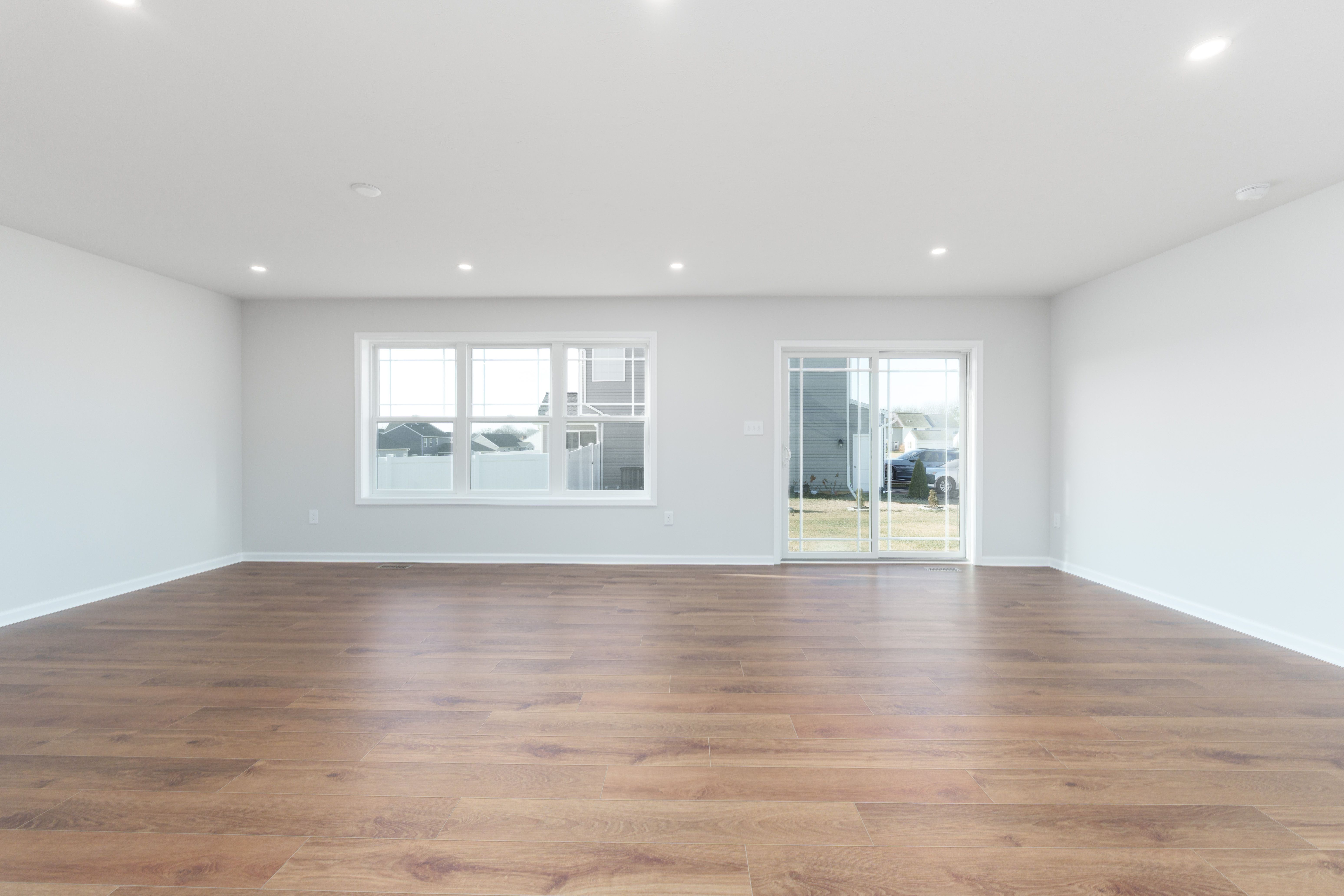 Spacious living area with luxury vinyl plank flooring, recessed lights, and backyard views