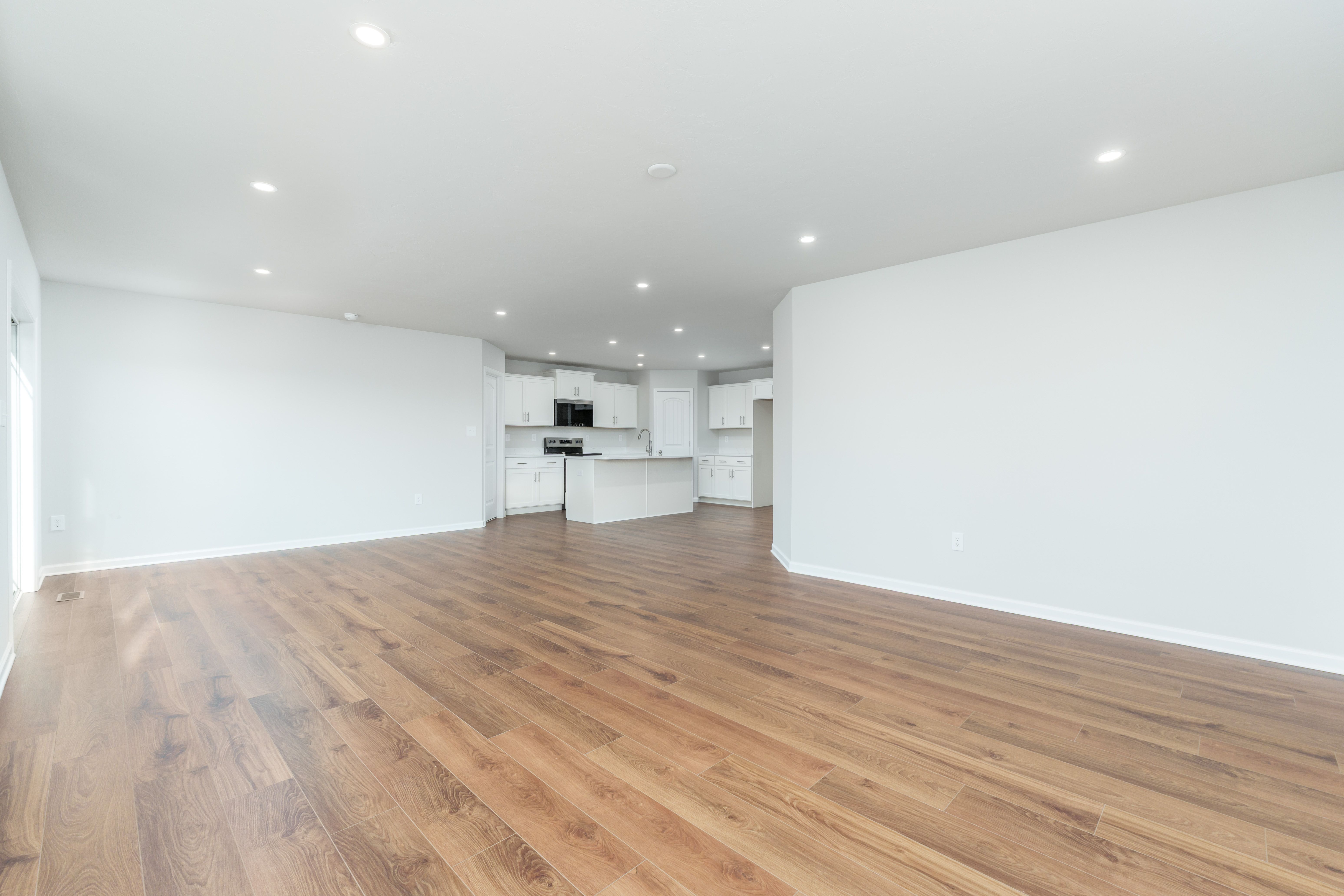 Great room with triple window, sliding patio door, and continuous luxury vinyl plank flooring