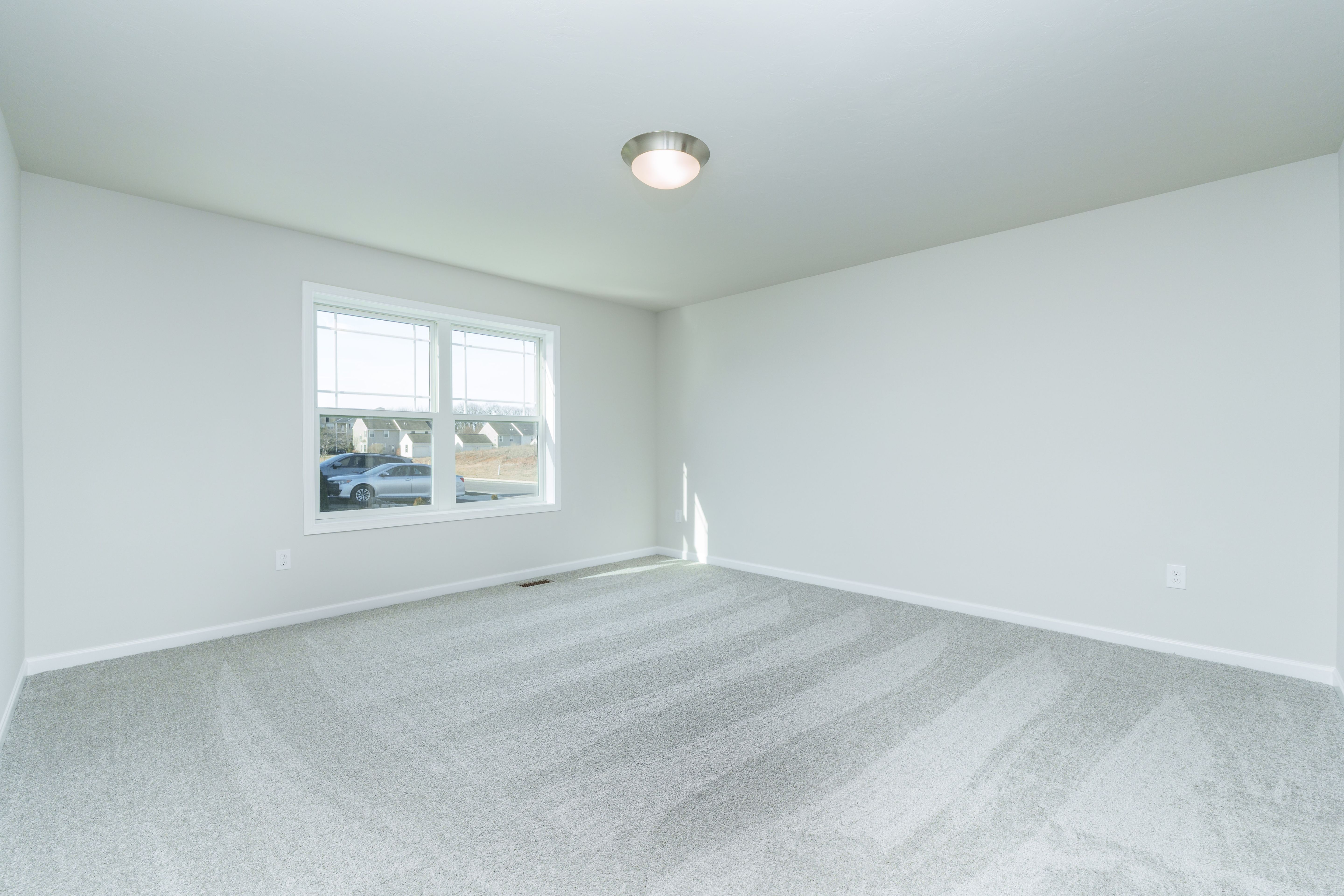 Owners bedroom with plush carpet, double window, and soft natural light