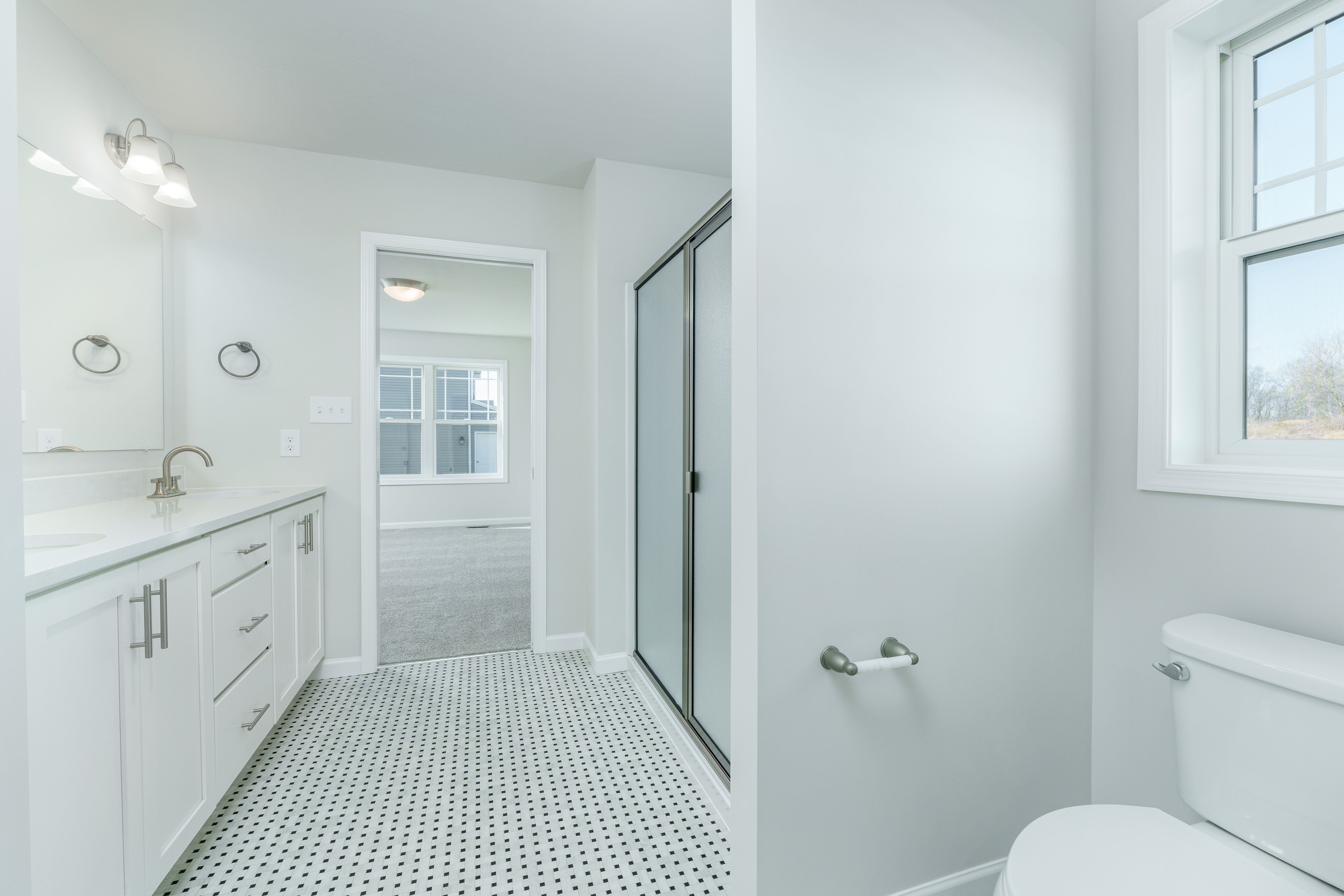 Owners bathroom with long double vanity, dual sinks, and black and white tile floor