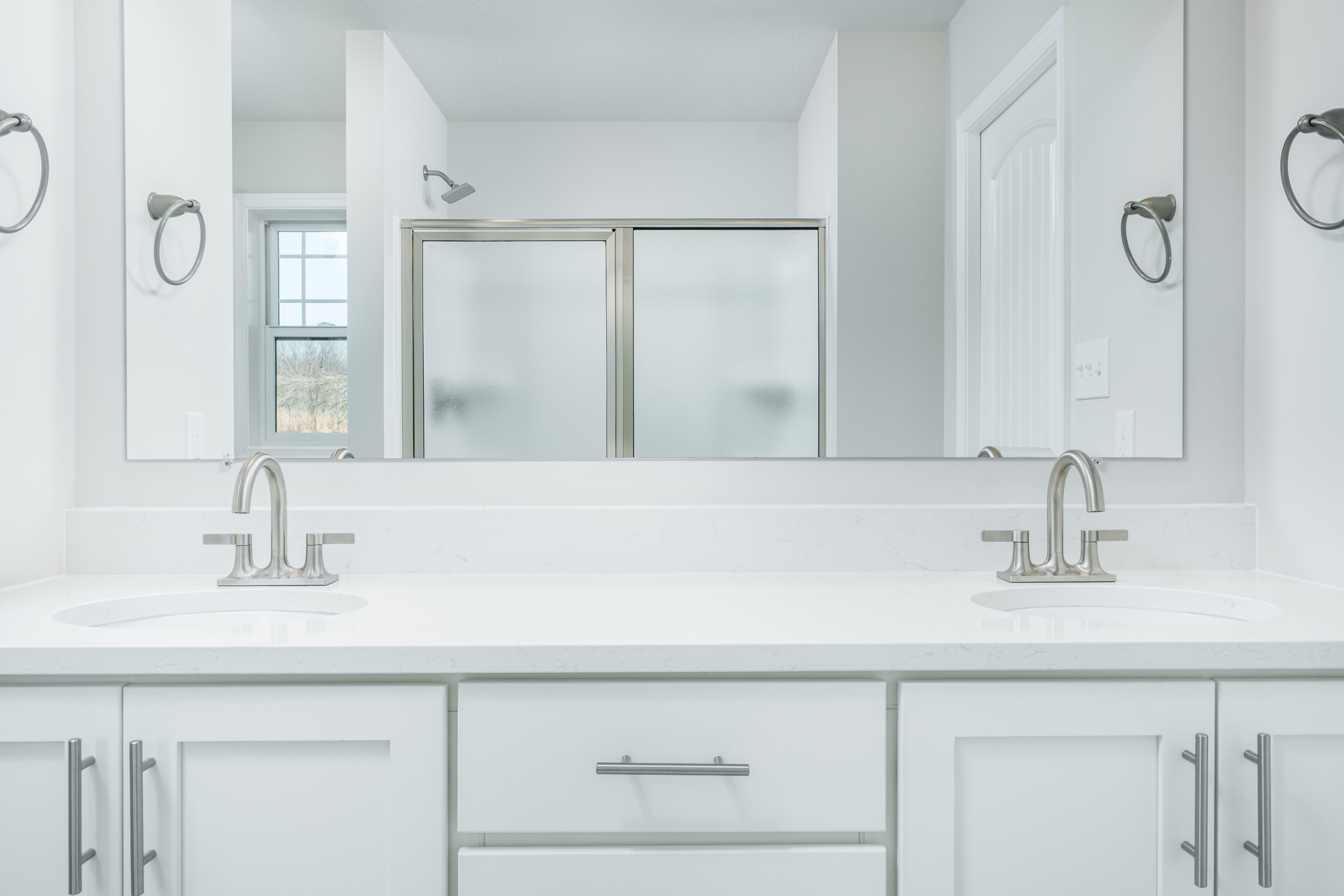 Owners bath vanity with dual sinks, white quartz countertop, and full-width mirror