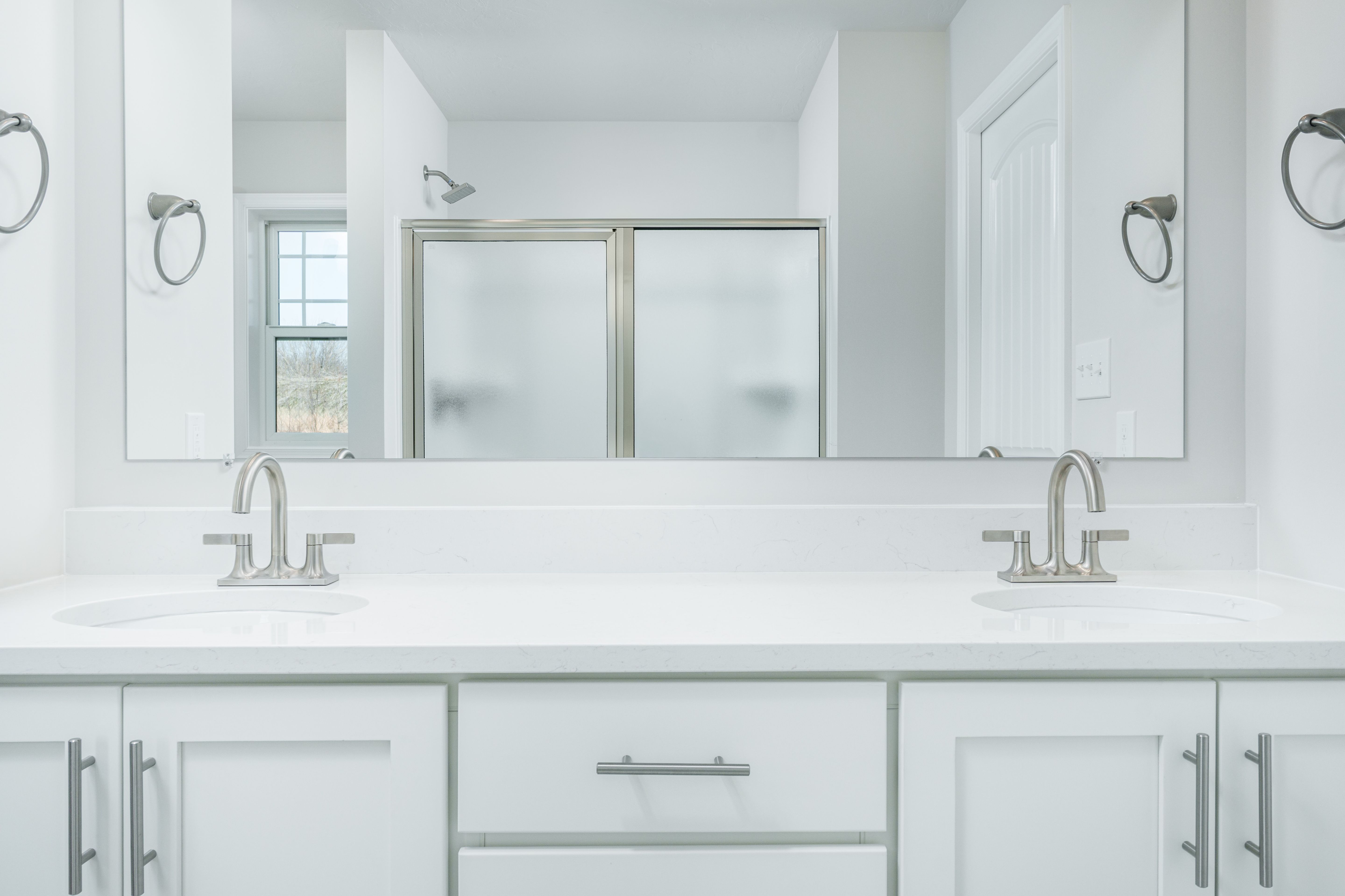 Owners bath vanity with dual sinks, white quartz countertop, and full-width mirror