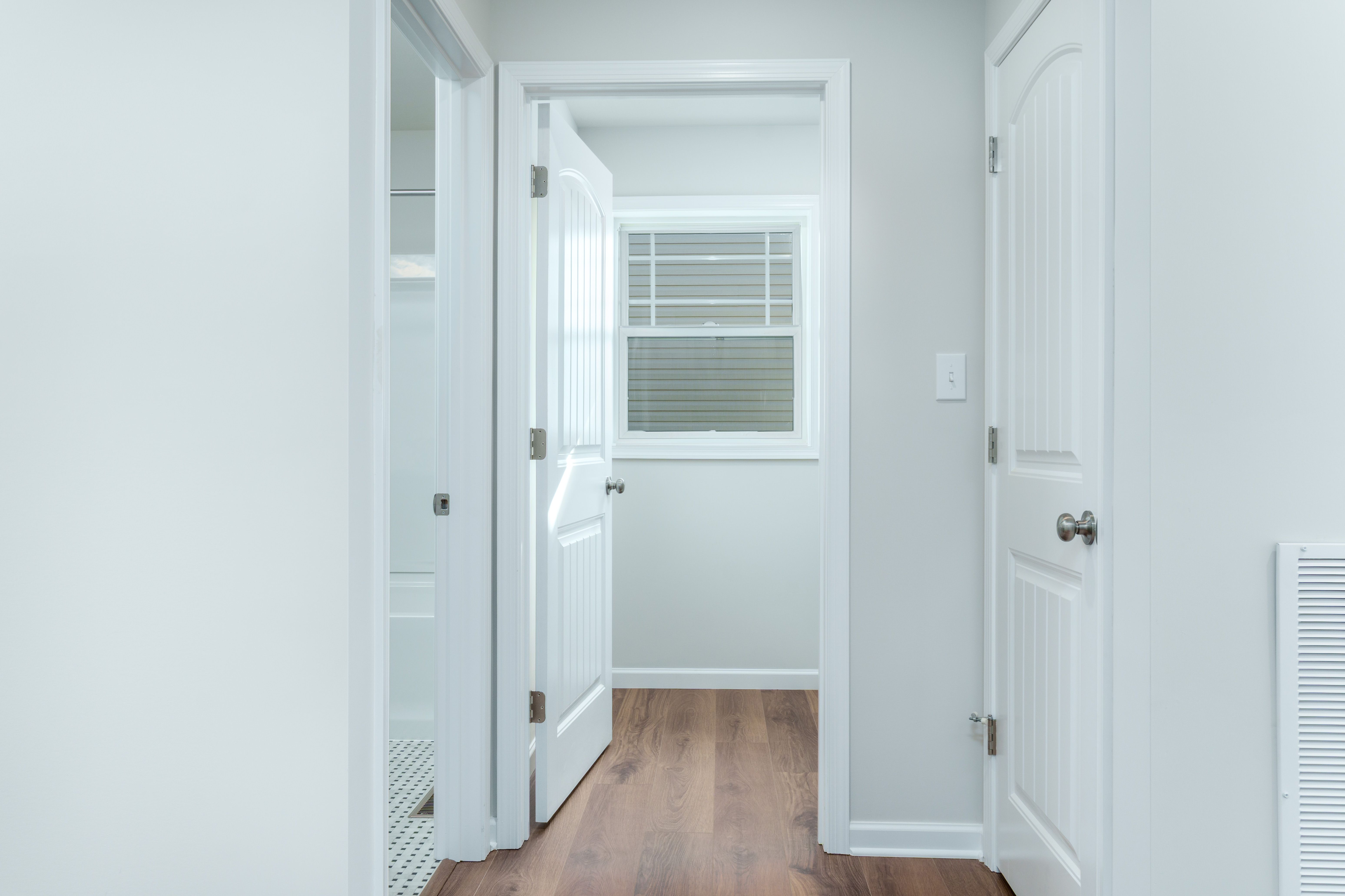 Main level hall with luxury vinyl plank flooring and open doors to bath and laundry
