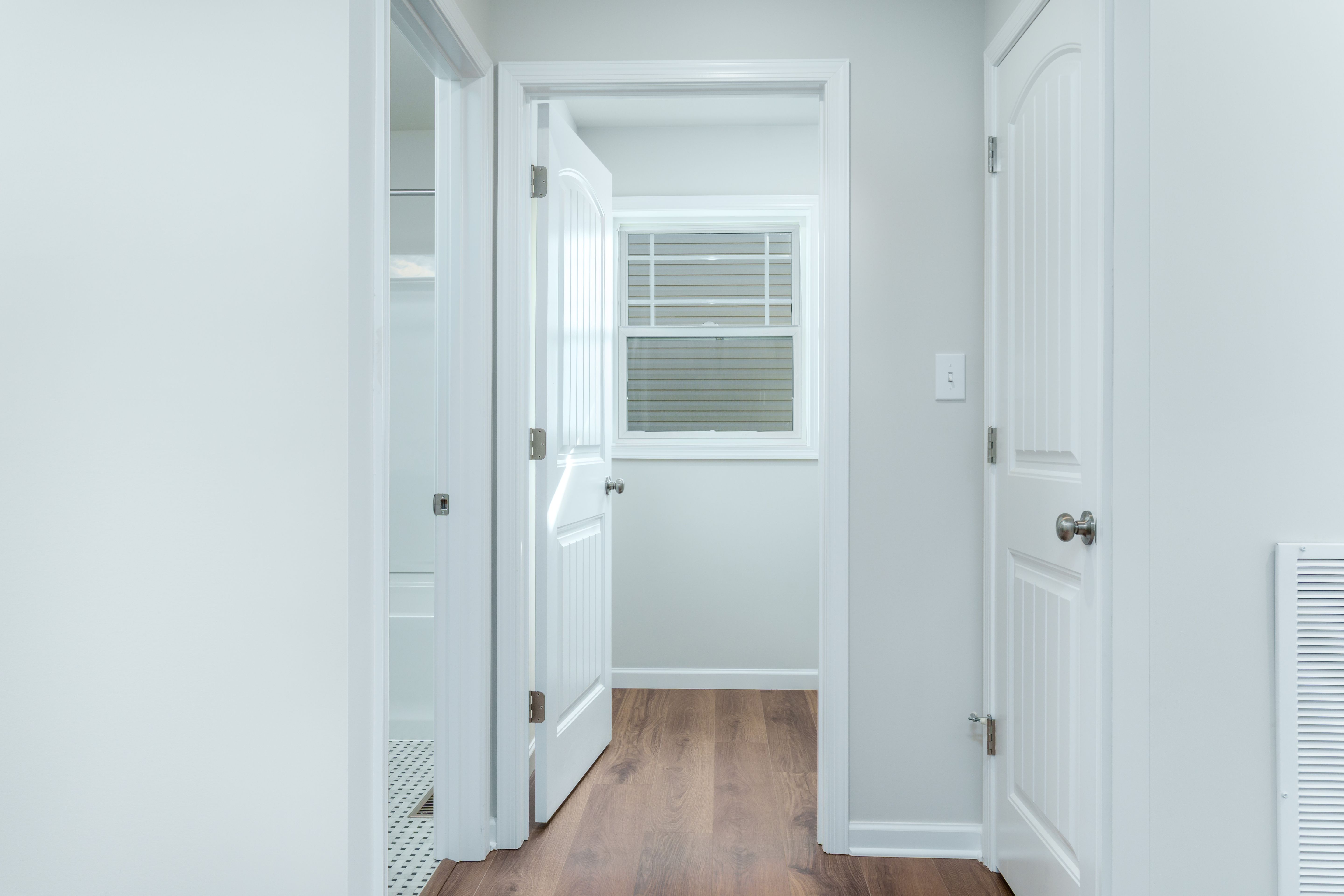 Main level hall with luxury vinyl plank flooring and open doors to bath and laundry