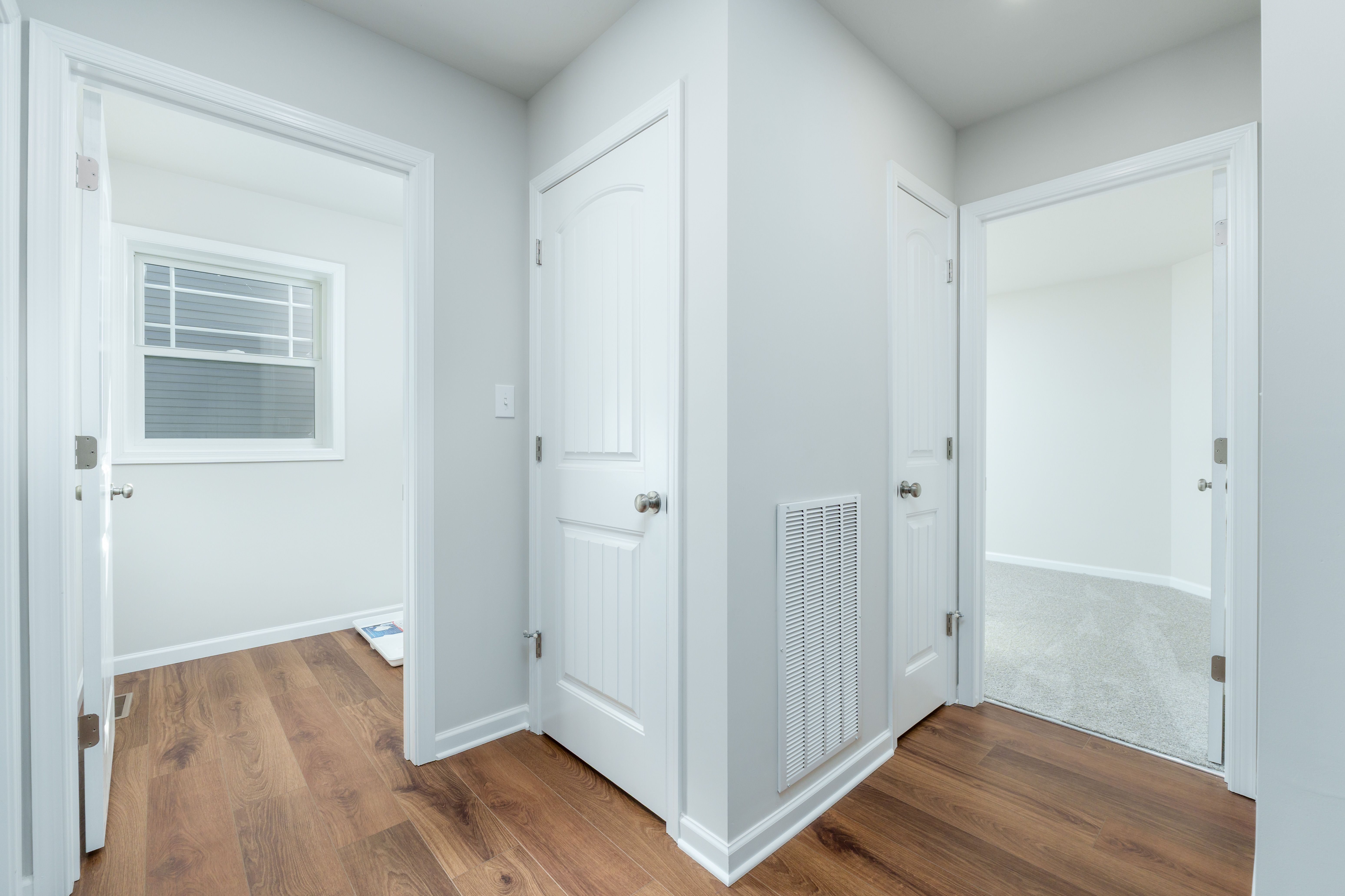 Interior hall with white paneled doors, floor vent, and luxury vinyl plank flooring