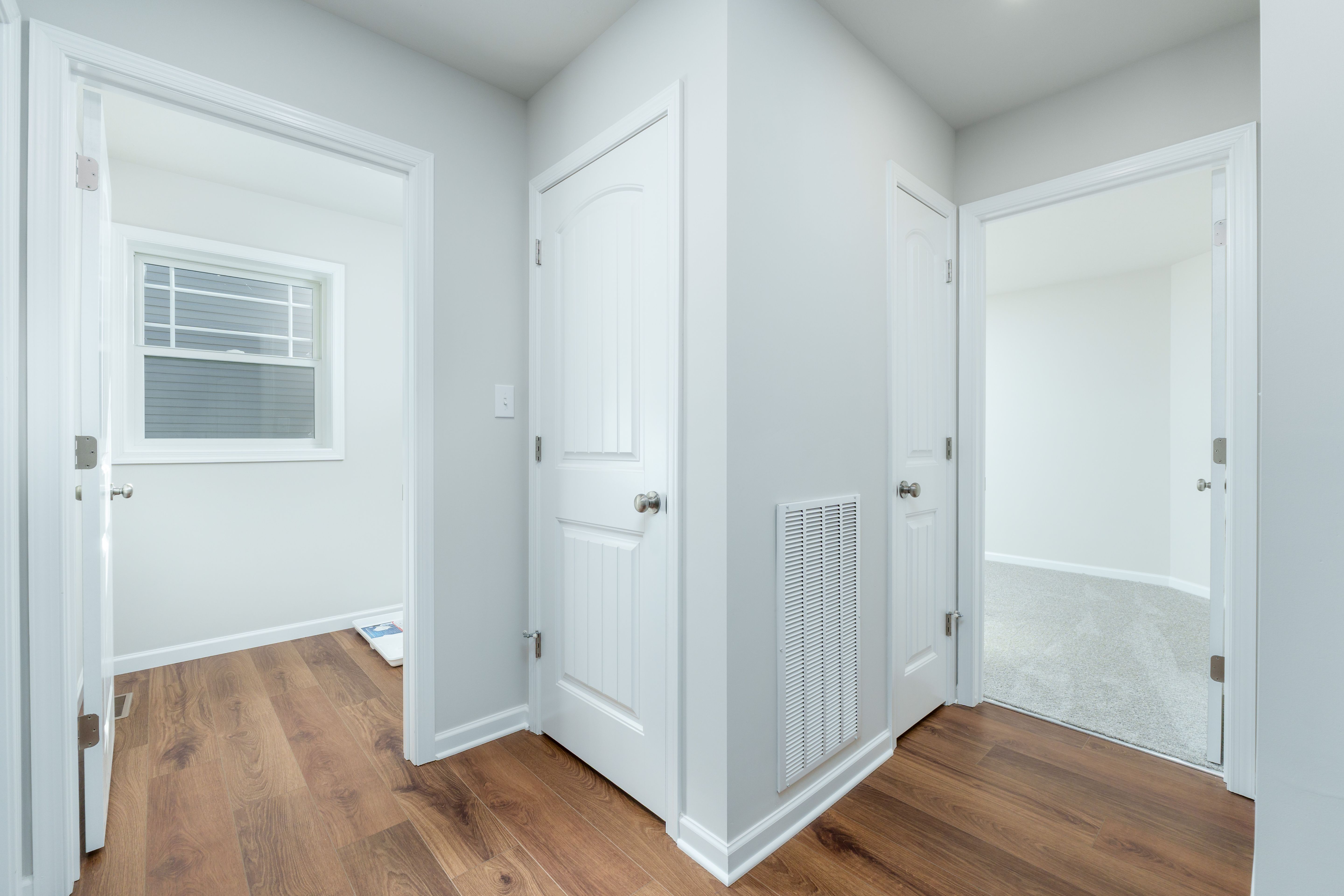 Interior hall with white paneled doors, floor vent, and luxury vinyl plank flooring