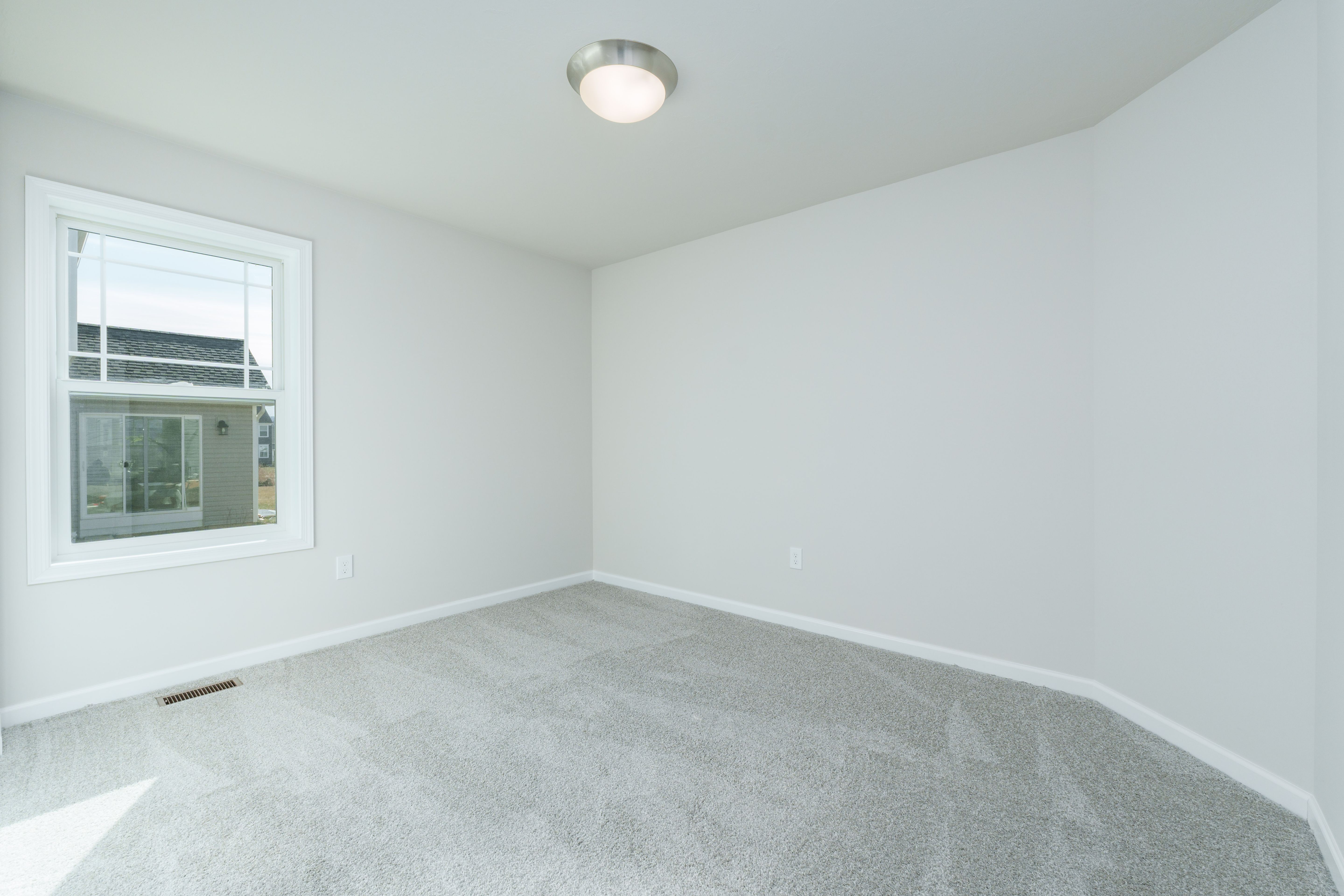 Bedroom with soft carpet, light gray walls, and single window with neighborhood view
